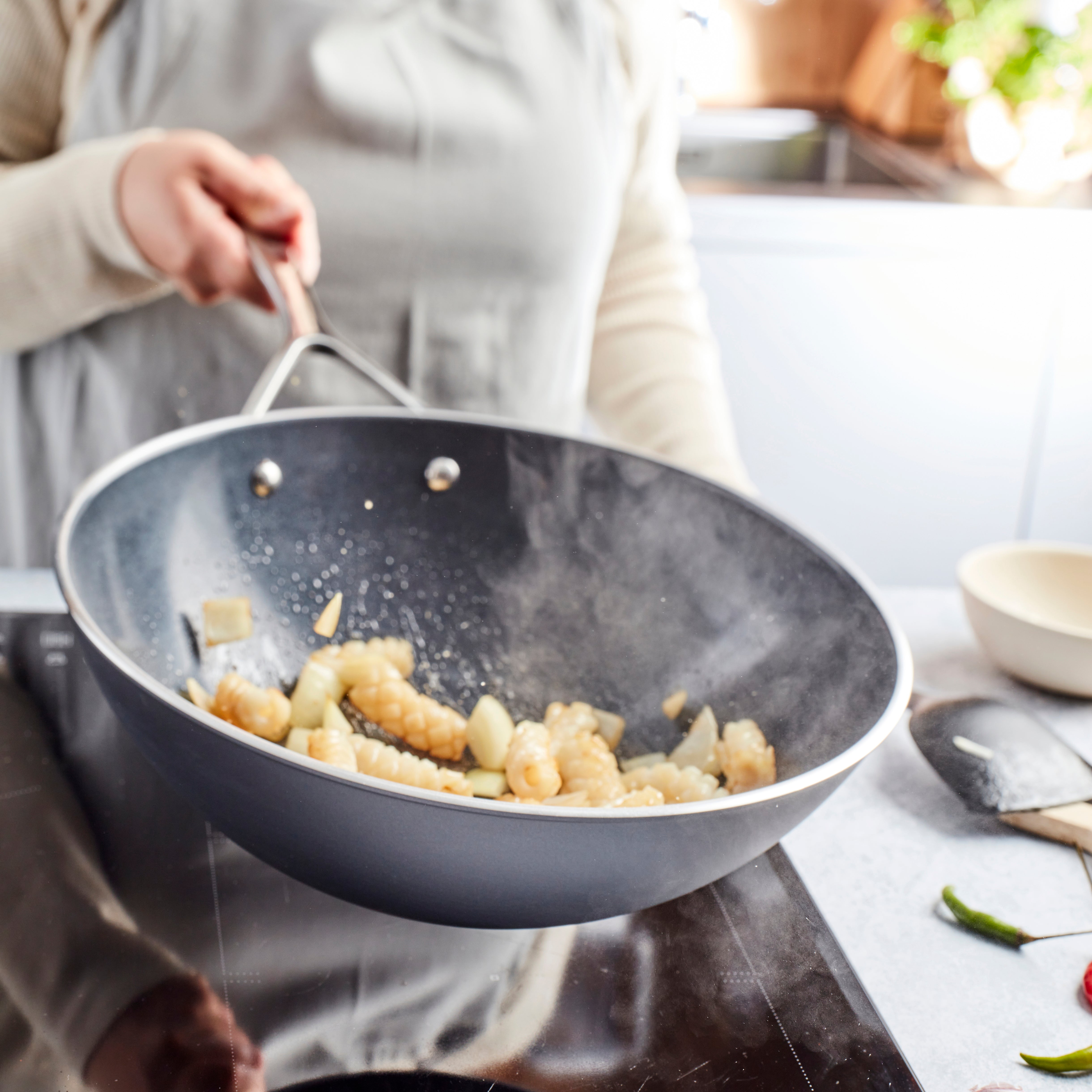 Side angle of ceramic wok with stainless steel handles and flared rim for easy pouring