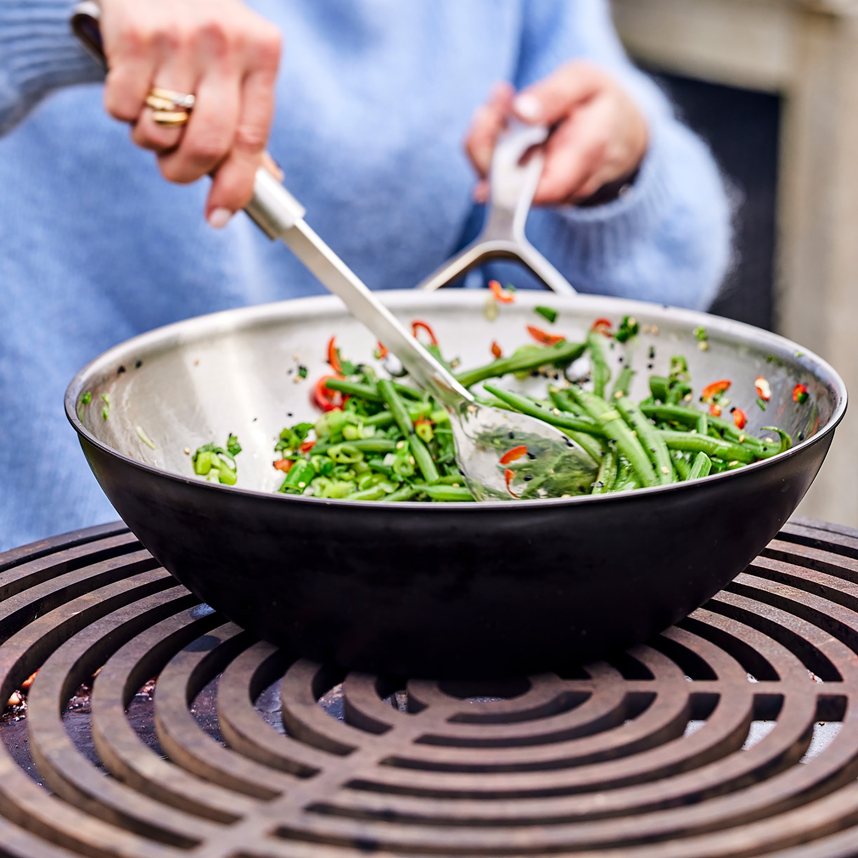 Stainless steel wok being used for outdoor cooking on a grill