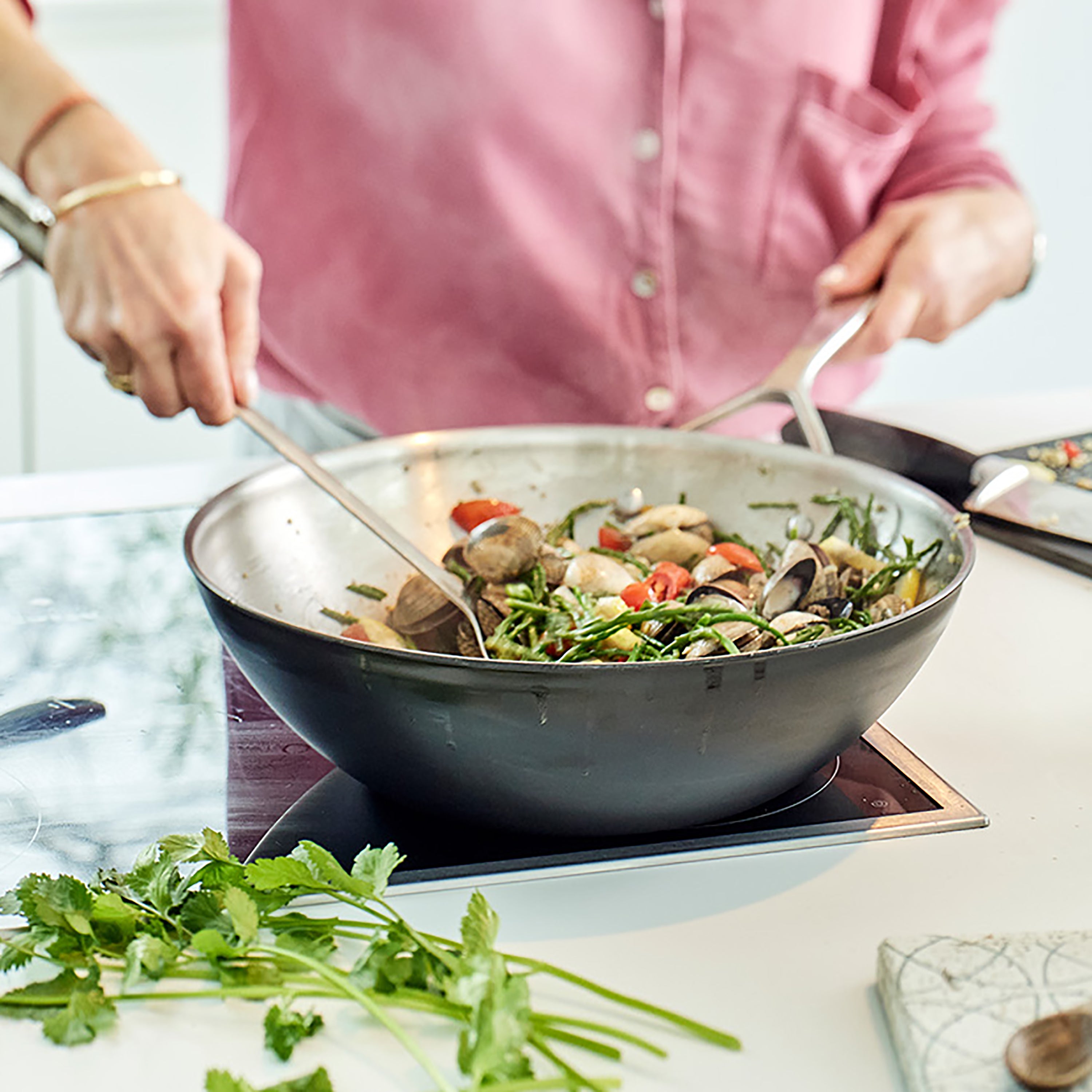 Stainless steel wok being used for outdoor cooking on a grill