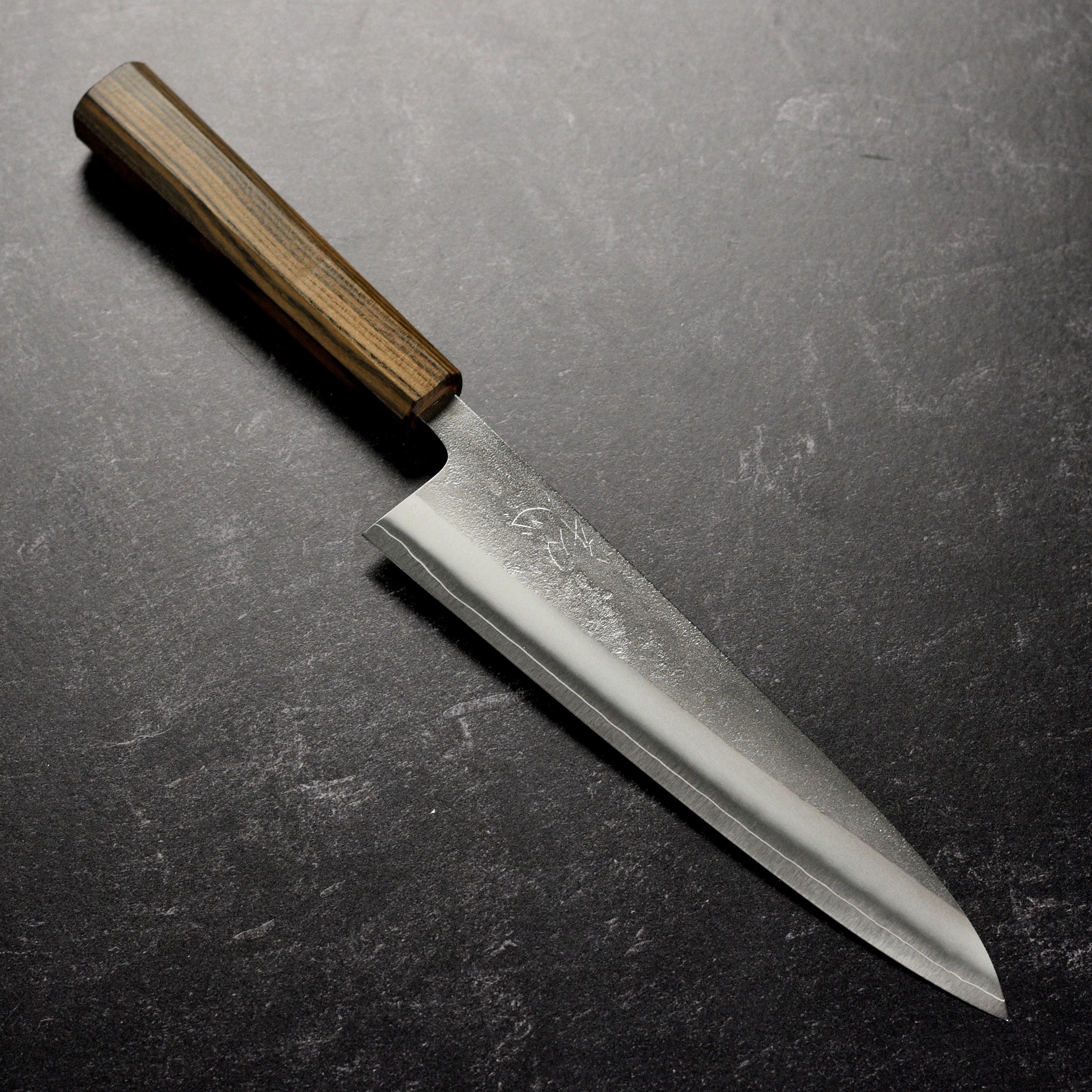 Yoshikane SKD gyuto knife on a wooden cutting board, showcasing its sharp blade and elegant handle.