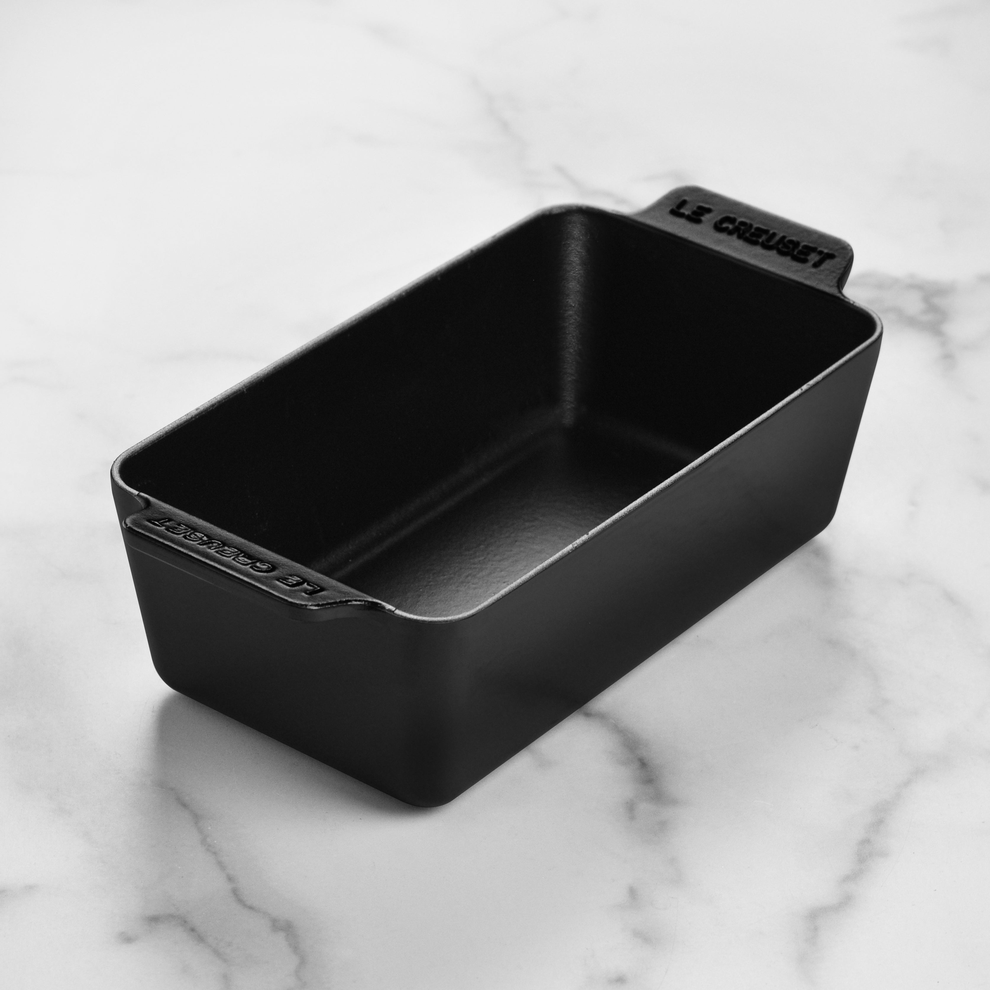 Loaf pan in use with freshly baked bread on a kitchen countertop
