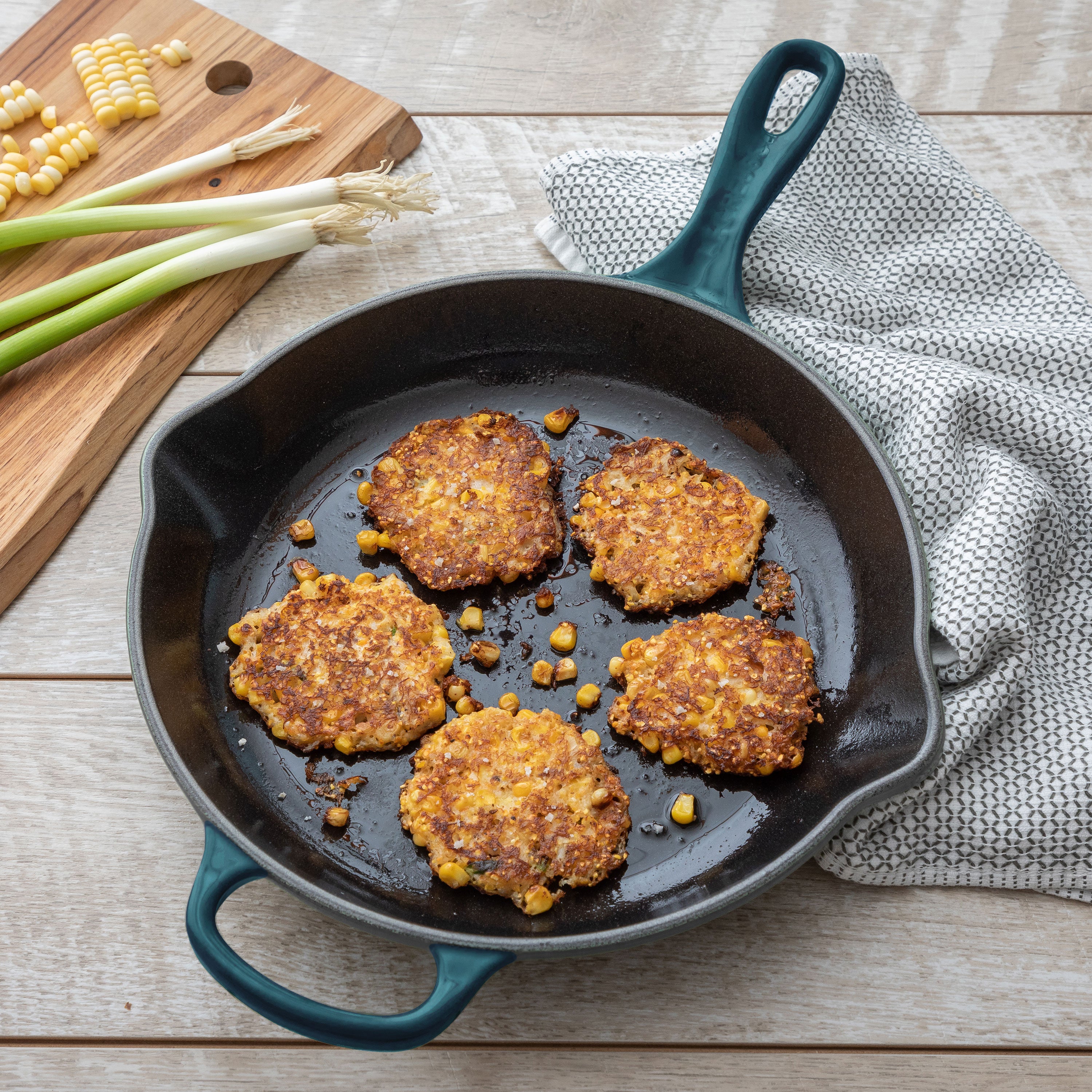 Top view of Le Creuset Deep Teal cast iron cookware set arranged on an induction cooktop
