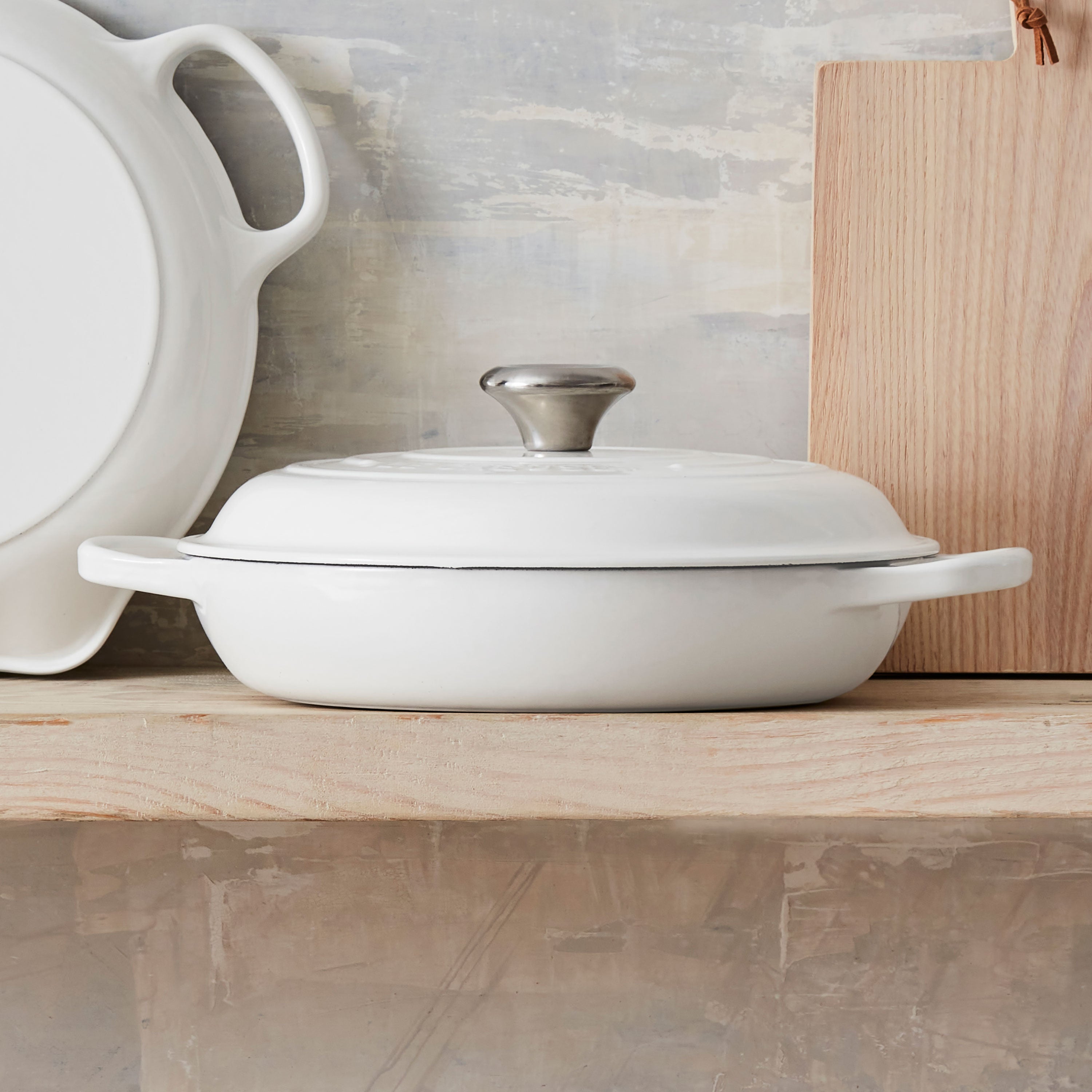 Le Creuset braiser in use on a gas stovetop, demonstrating versatility across various cooktops.