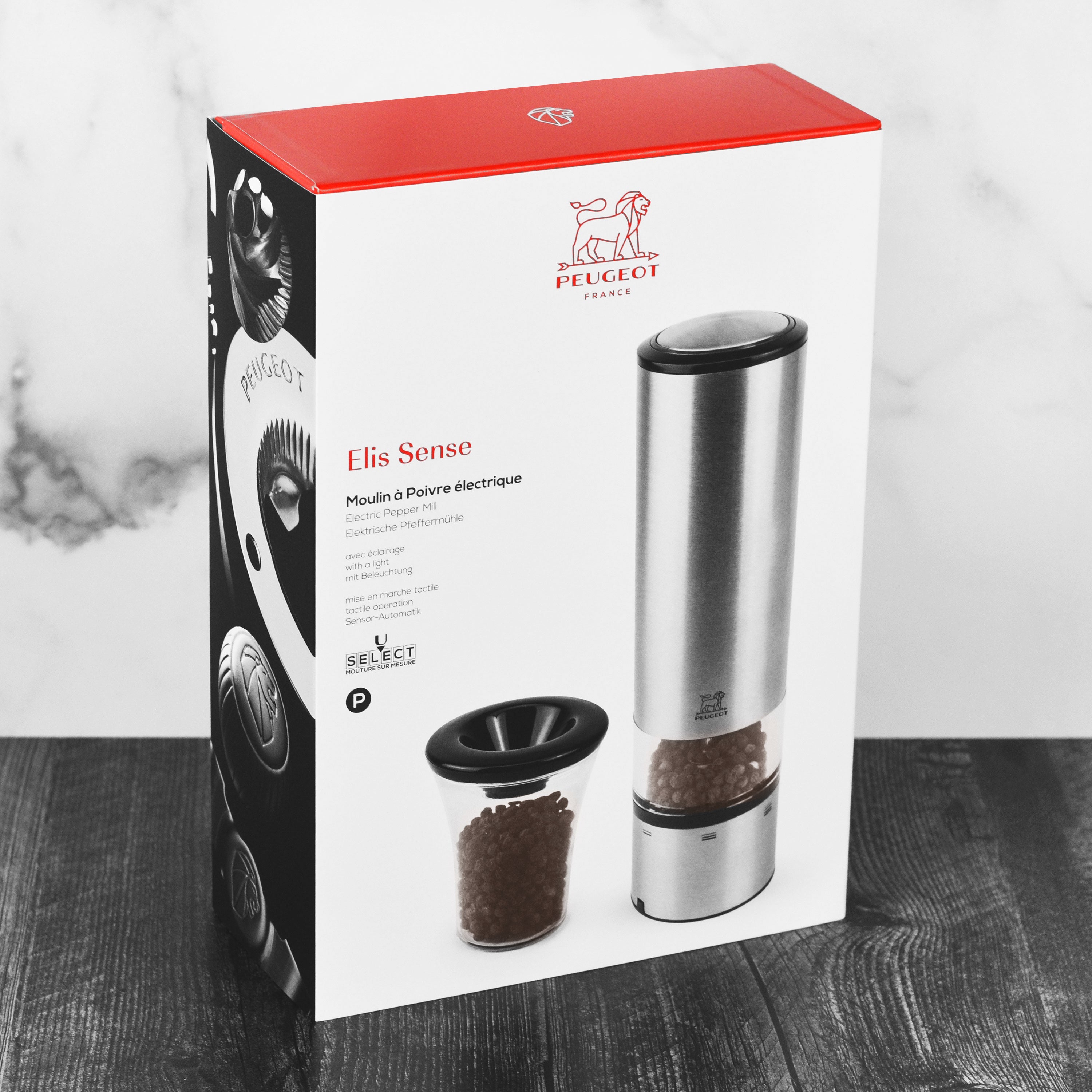 Peugeot Elis Sense electric pepper mill displayed on a dining table, highlighting its elegant design.