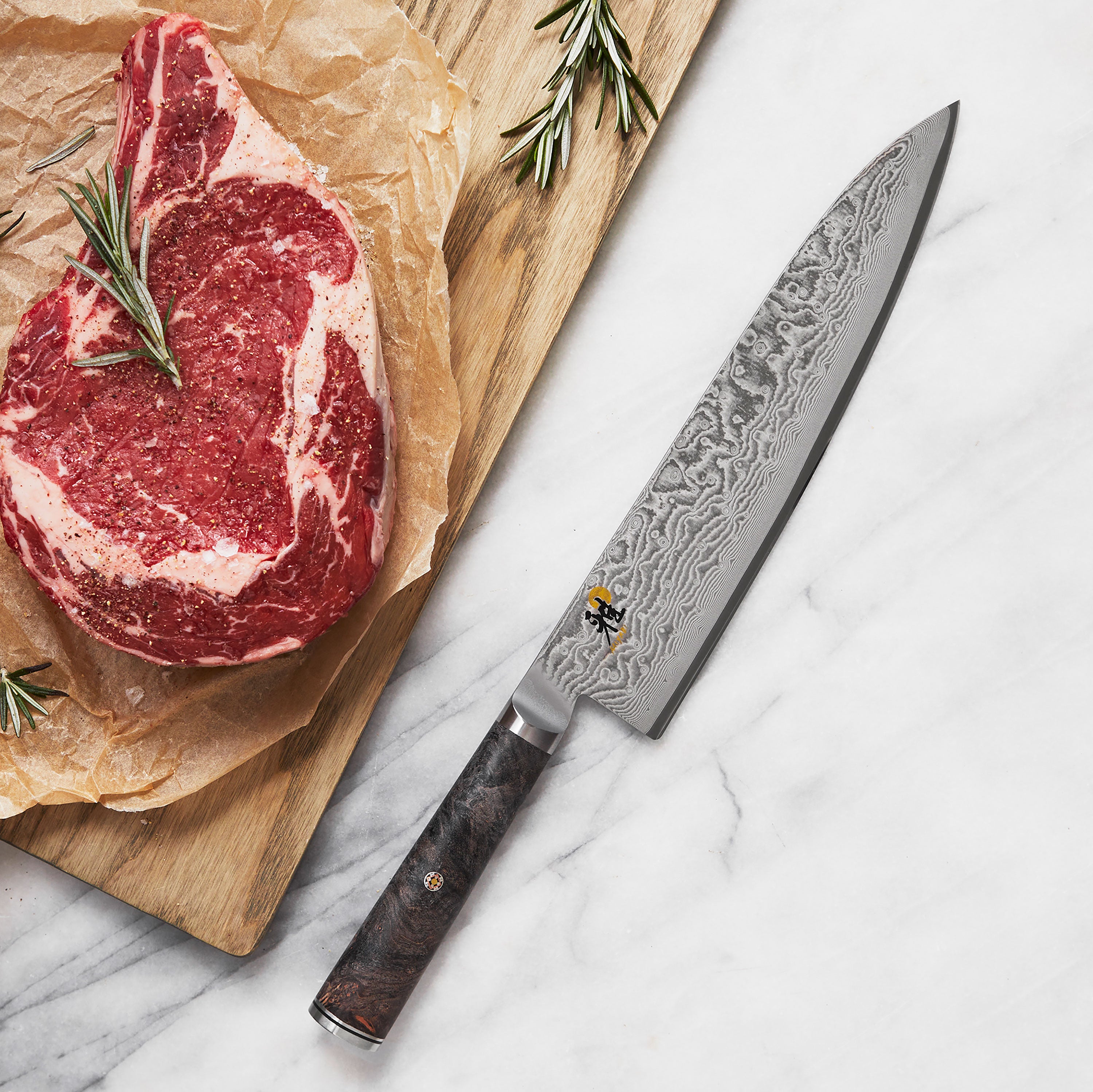 Close-up of the Miyabi Black 9.5" chefs knife blade, highlighting the Damascus pattern and sharp edge.