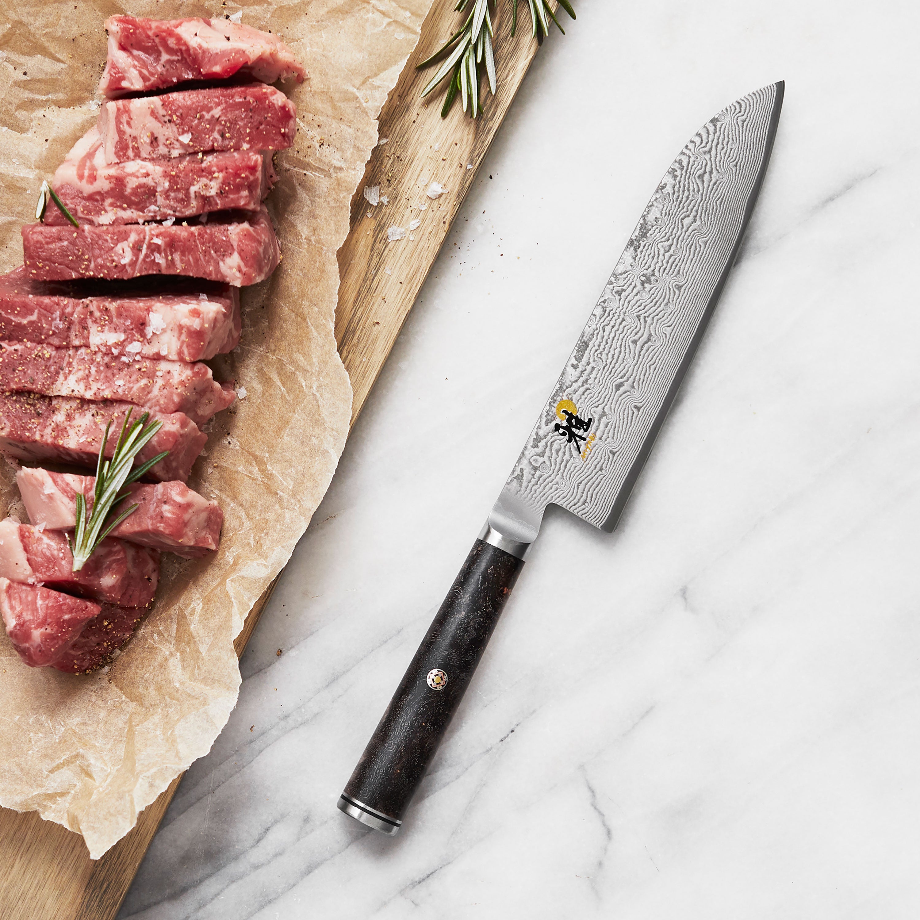 Close-up of the Miyabi Black Santoku Knifes Damascus blade and handle.