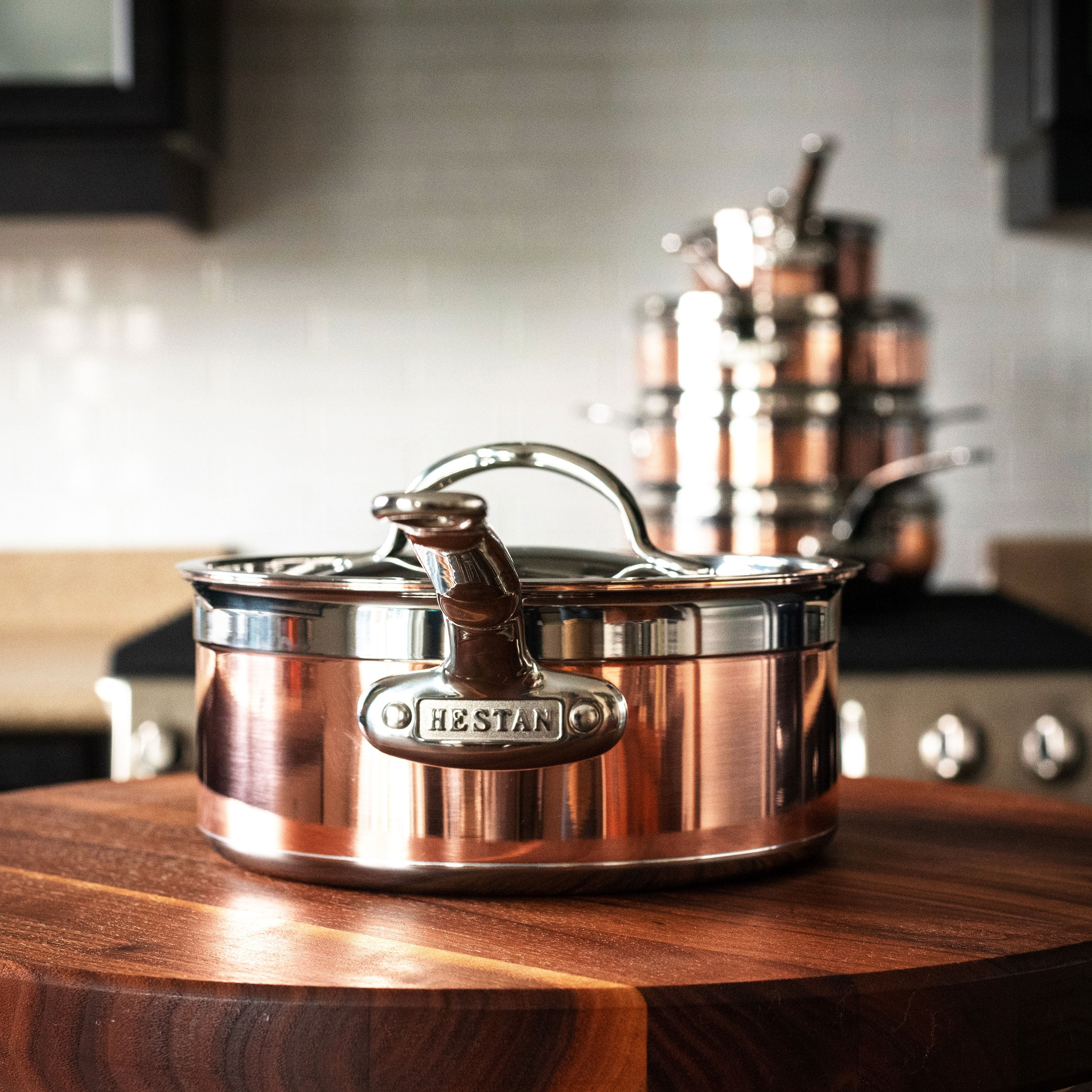 Close-up view of Hestan CopperBond induction cookware with riveted handles and polished stainless steel lid.