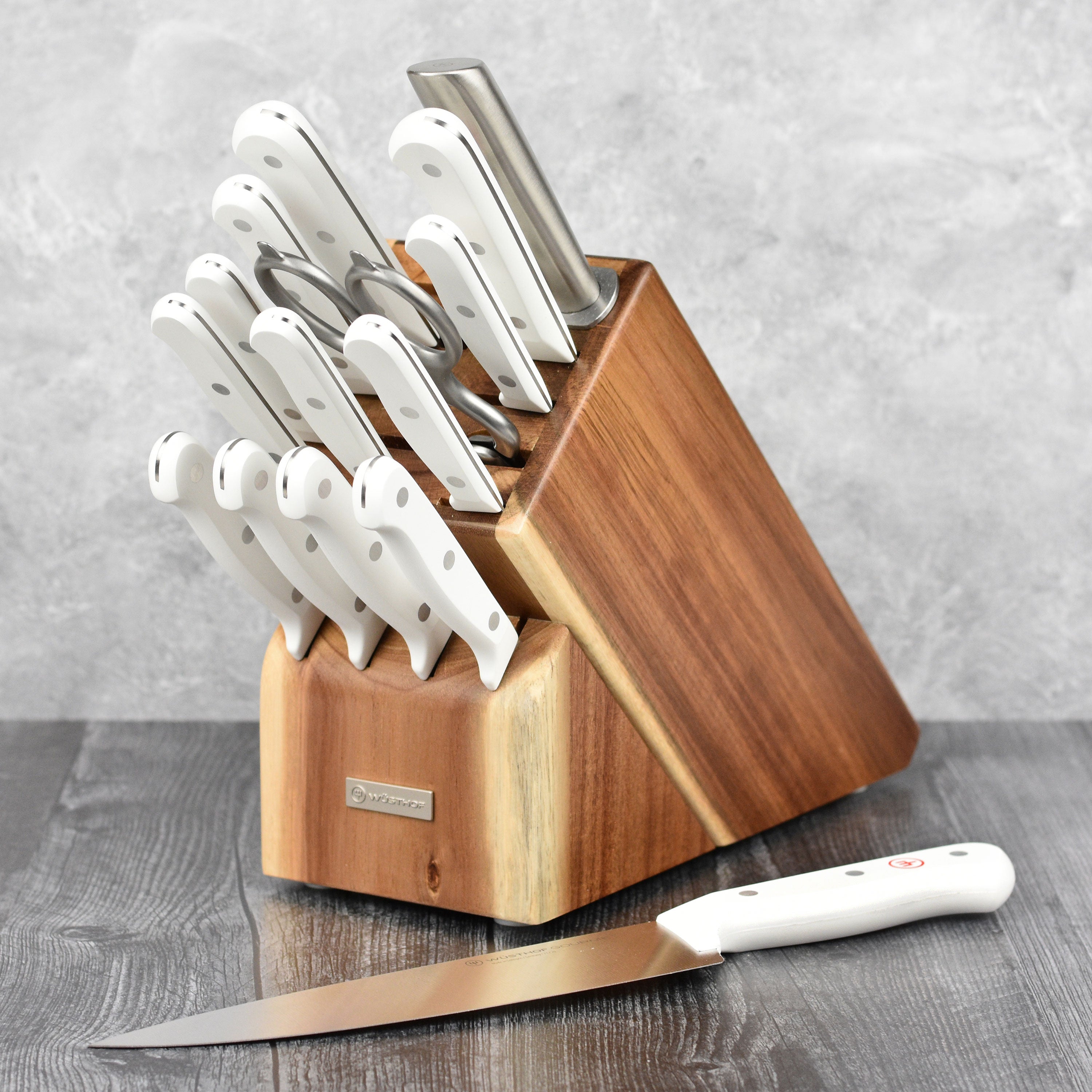 Wusthof Santoku knife with white handle cutting vegetables on a board.