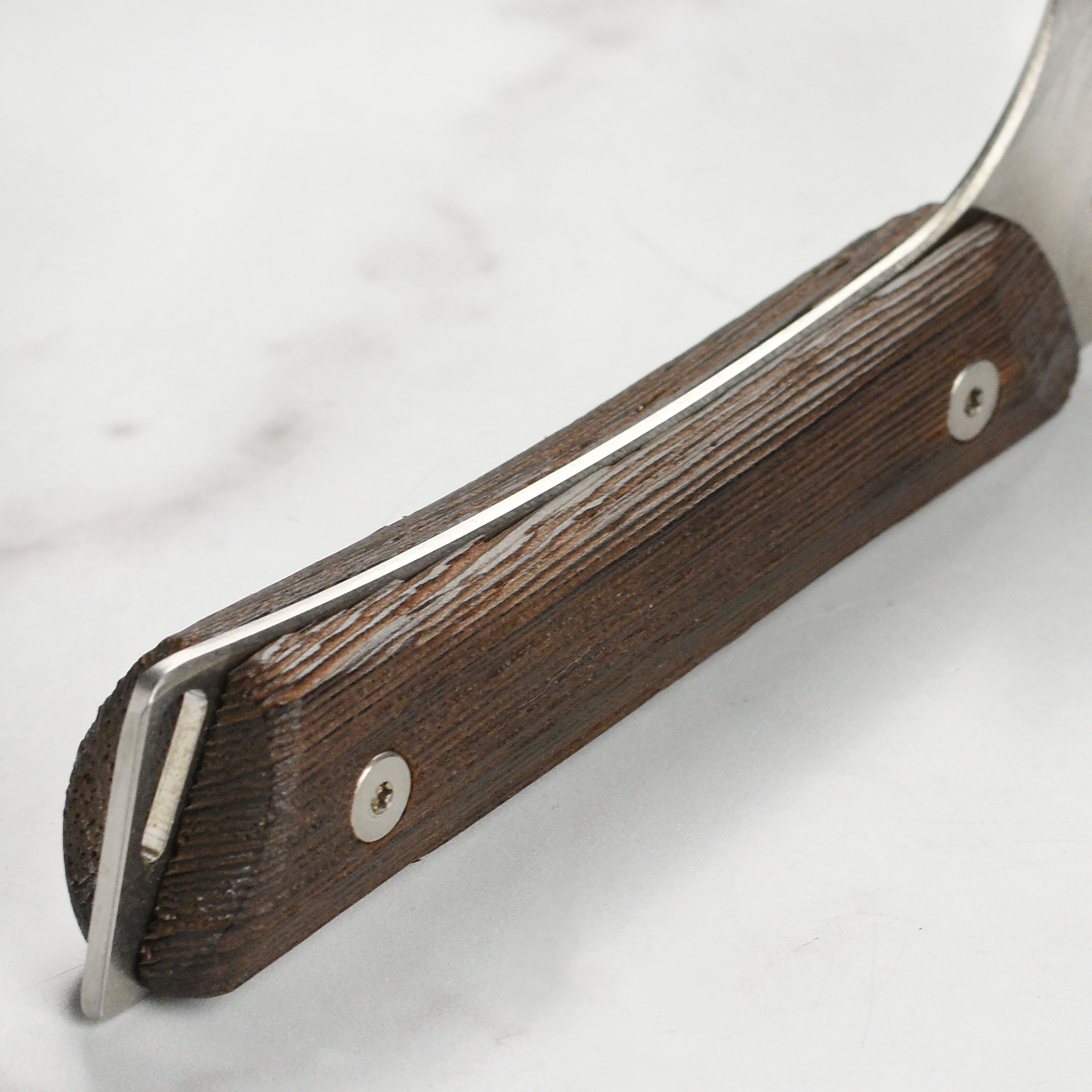 Close-up of Shun Kanso Santoku knife highlighting the high-carbon stainless steel blade and rustic finish.