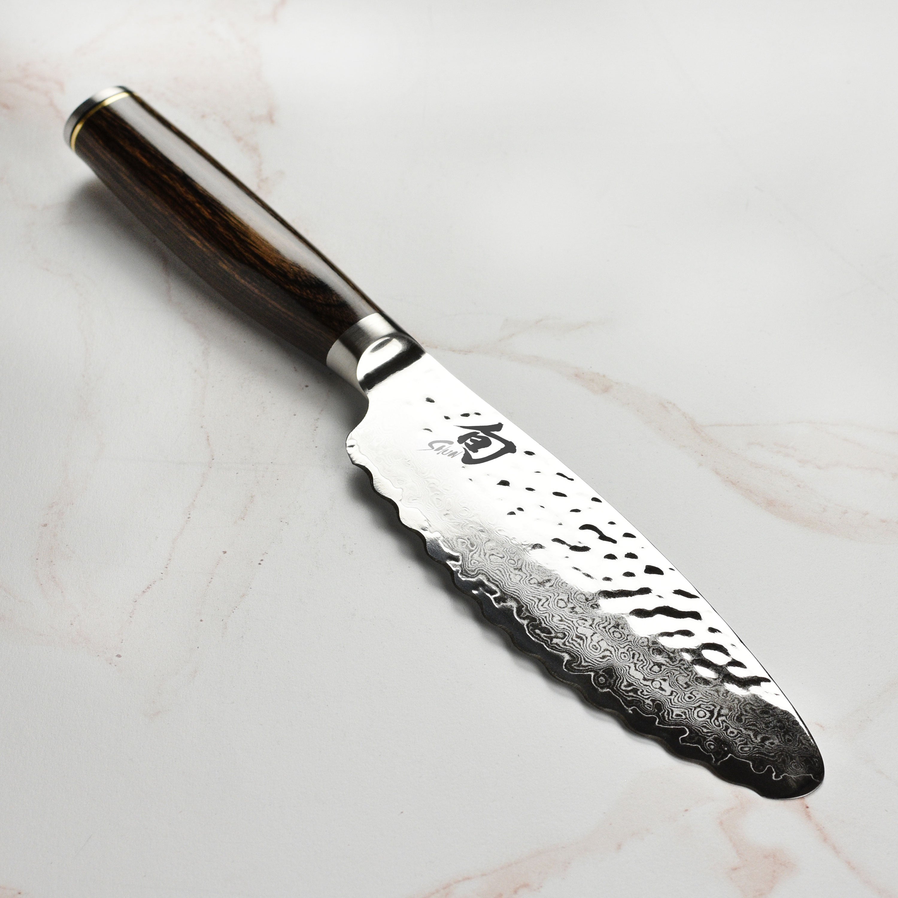 Shun Premier 6 inch utility knife on cutting board with vegetables, showcasing hammered Tsuchime finish
