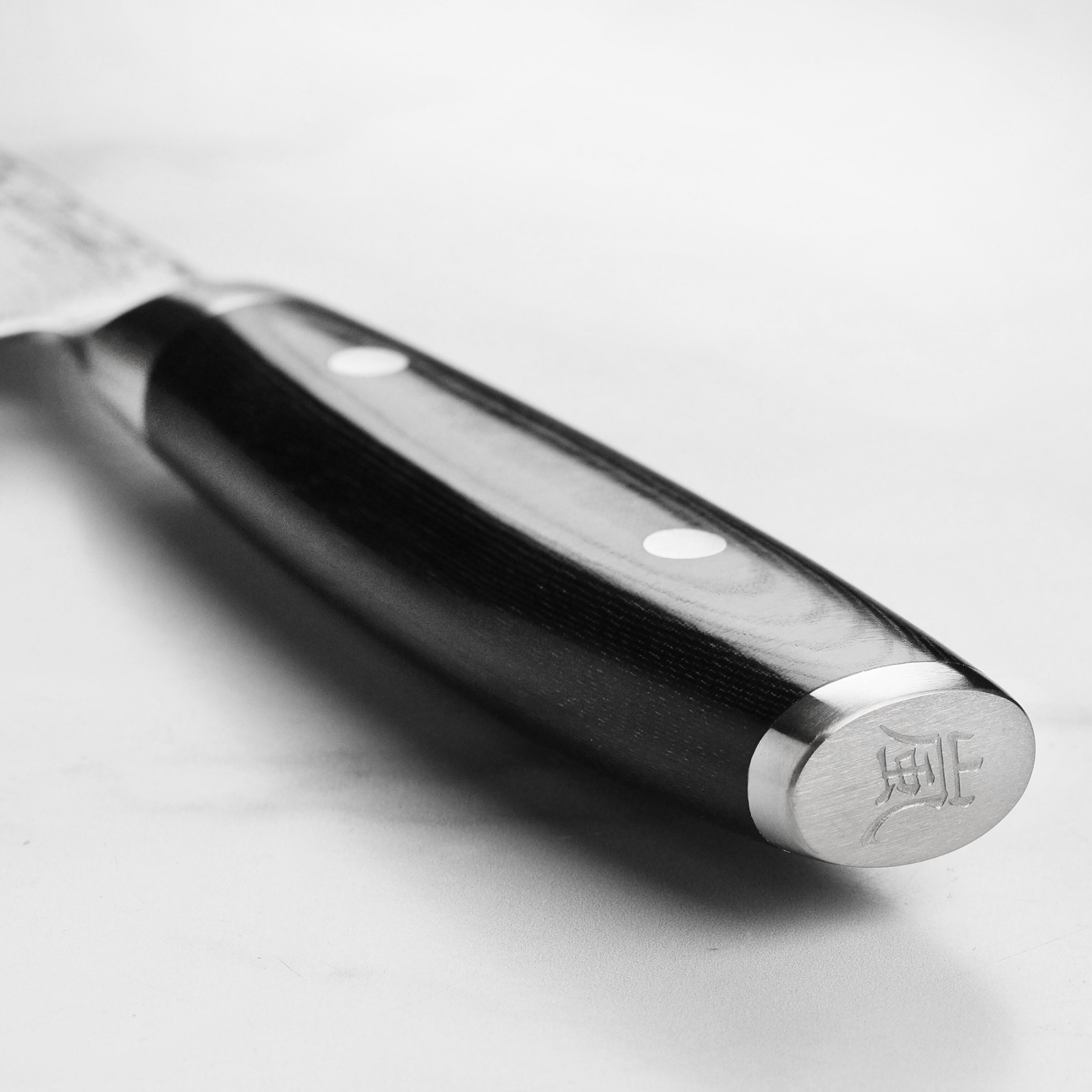Yaxell Ran Plus 9.5" Chefs Knife displayed on a wooden cutting board, highlighting its sharpness.