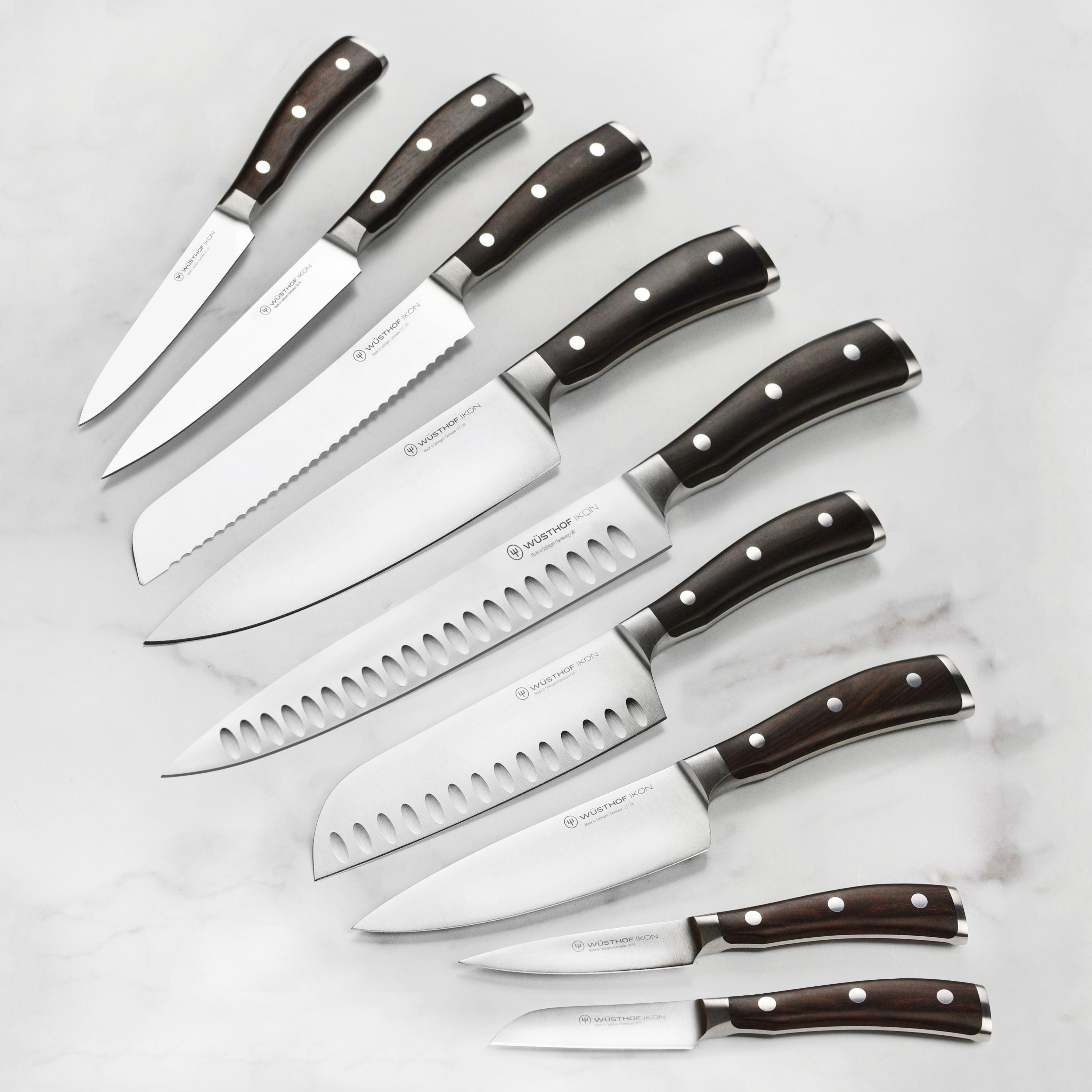 Set of high-carbon kitchen knives with blackwood handles on a cutting board