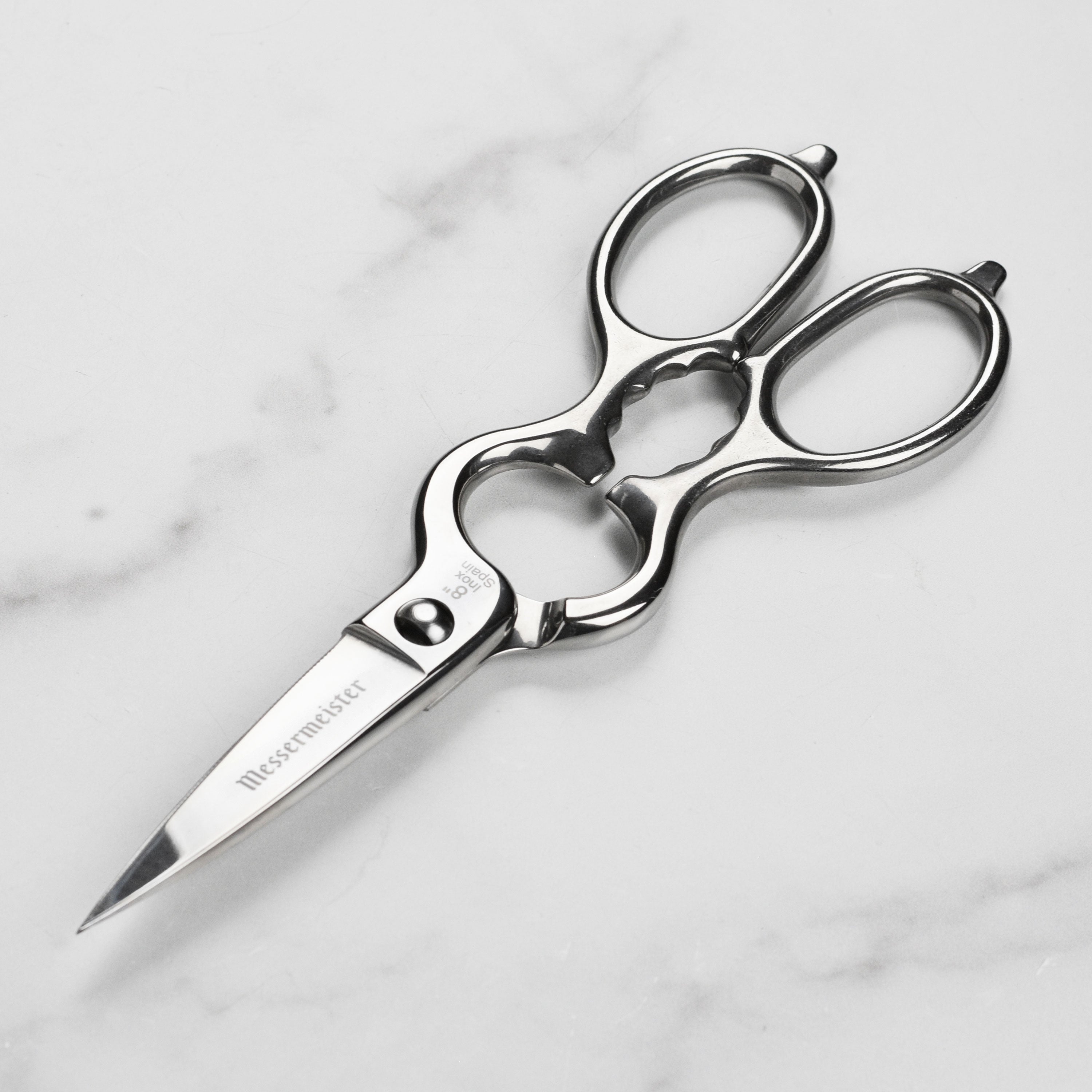 Messermeister kitchen shears cutting herbs on a wooden board.