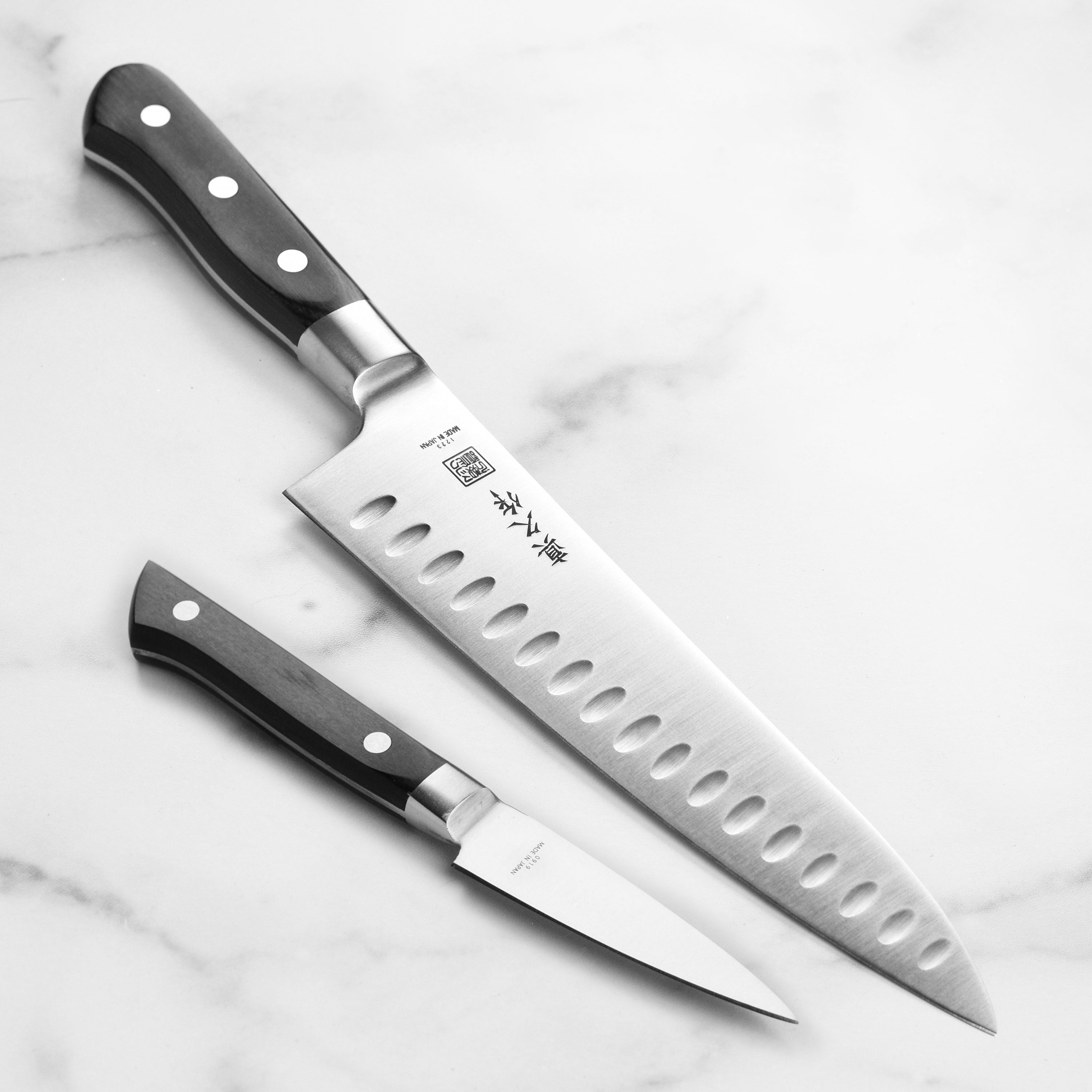Close-up of MAC Japanese chef knife with hollow edge blade slicing vegetables