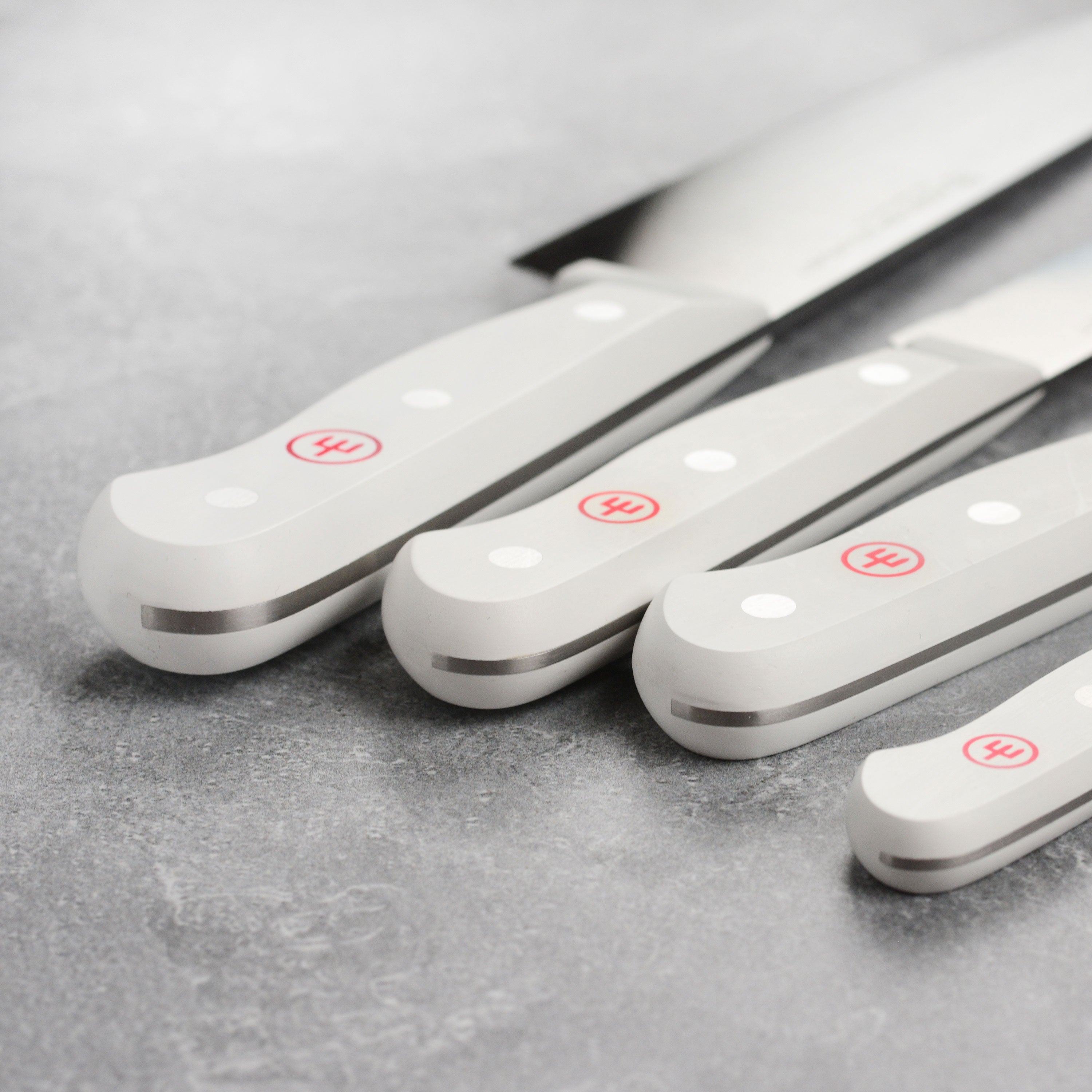 Wusthof Gourmet 12-piece German kitchen knife set with white handles on a wooden cutting board