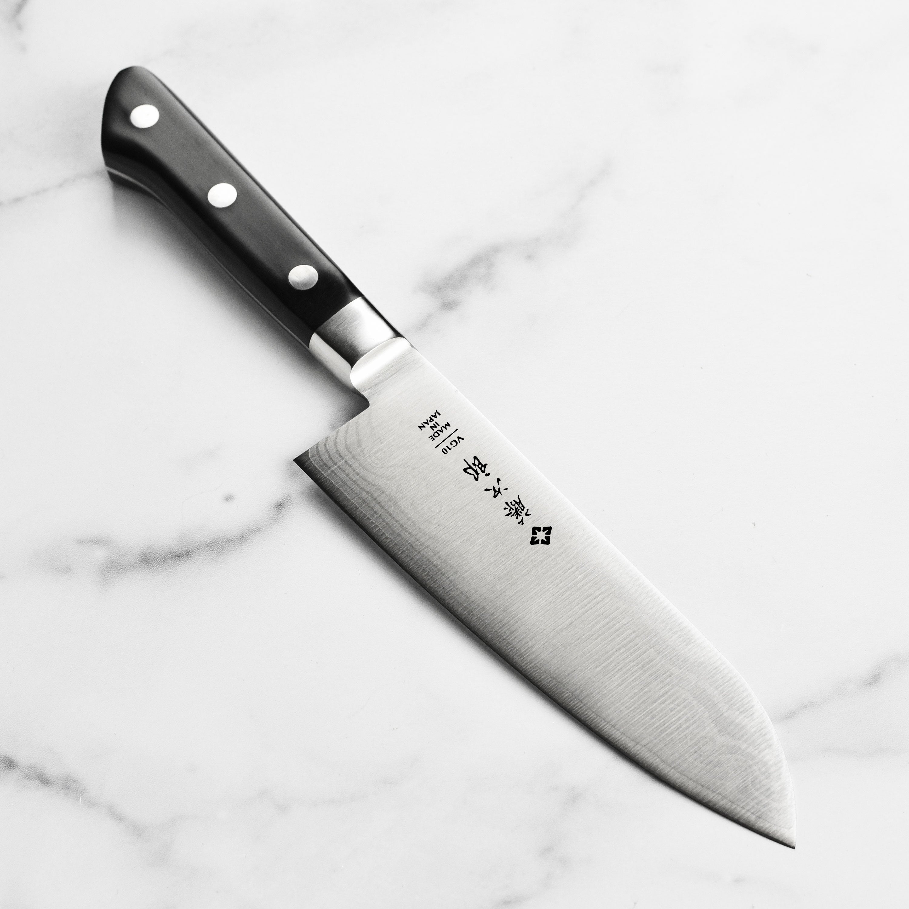 Close-up of the Tojiro Classic Damascus Santoku Knife blade, highlighting its intricate pattern and sharp edge.