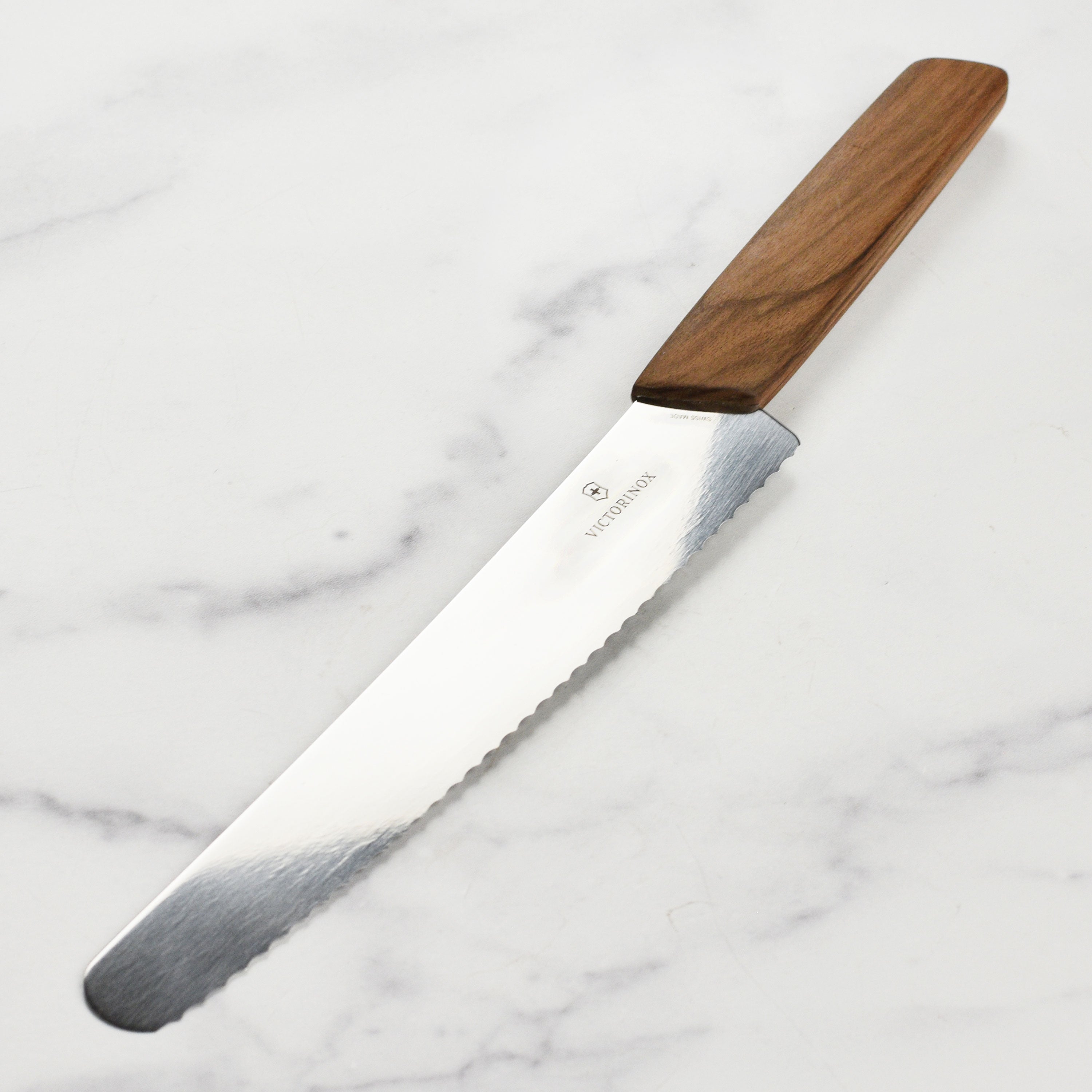 Victorinox Swiss Modern 8.5" Bread Knife with serrated edge and wooden handle, placed on a kitchen countertop.