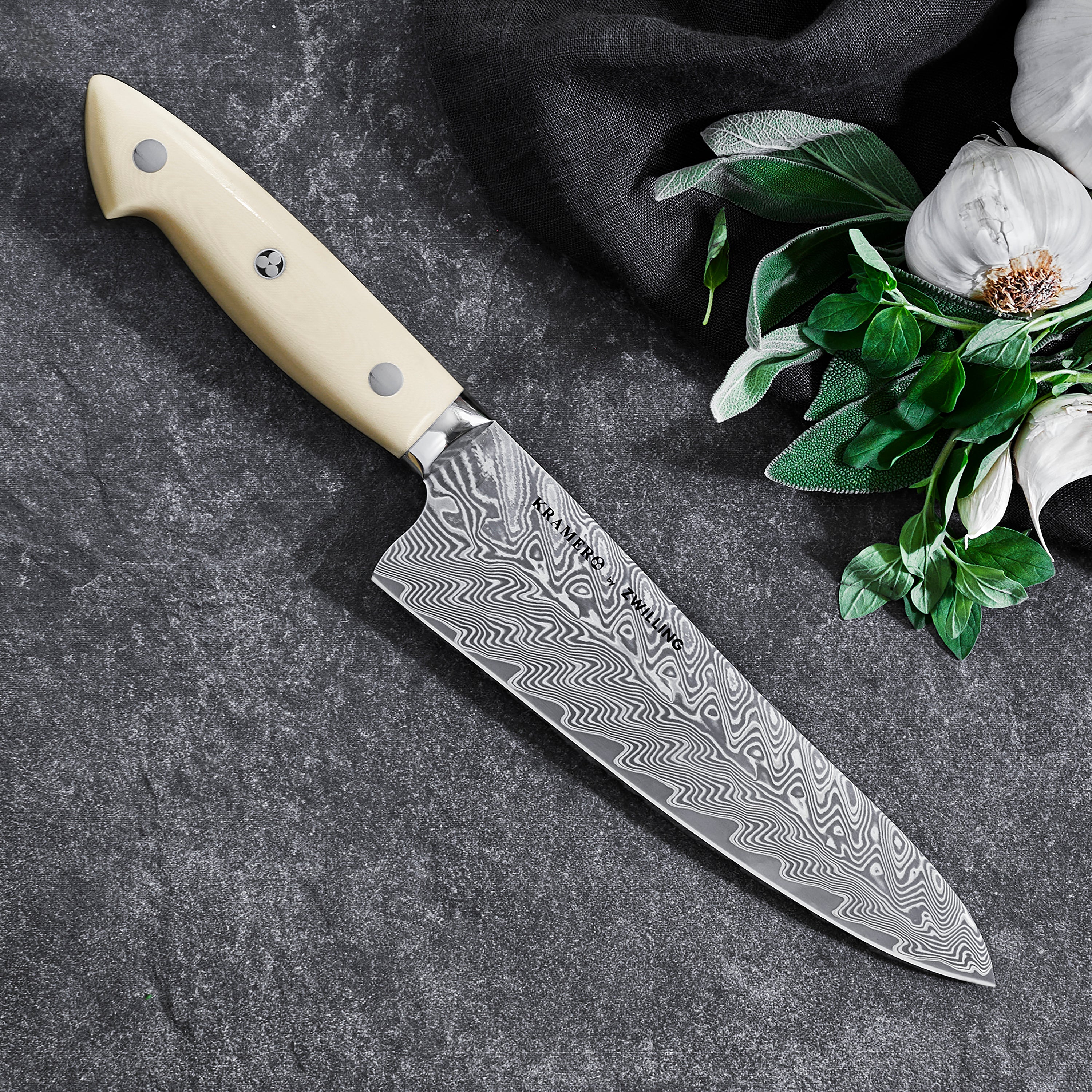 Kramer Cumulus Santoku Knife in action, slicing fresh vegetables on a wooden cutting board.