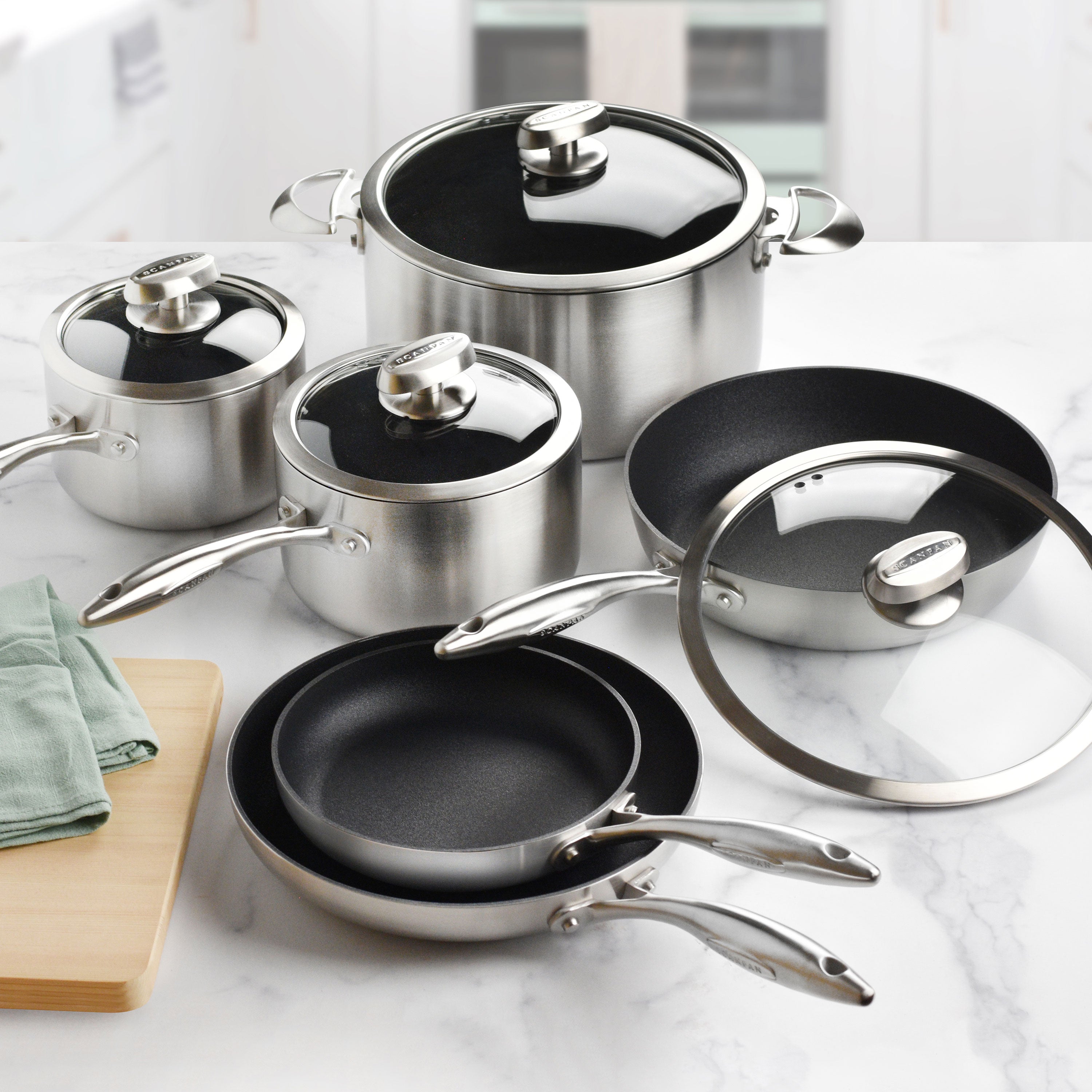Stainless steel nonstick cookware set with glass lids on a modern stove
