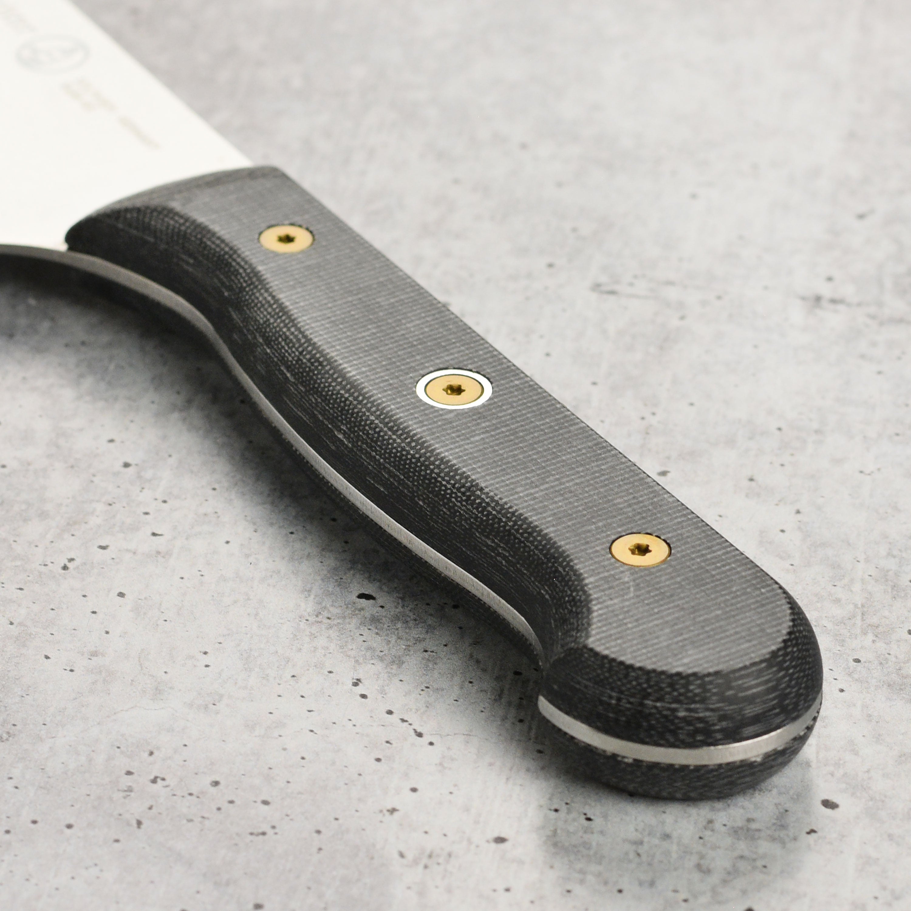 Close-up of custom micarta handle with triple rivets, highlighting ergonomic bolster for secure grip.