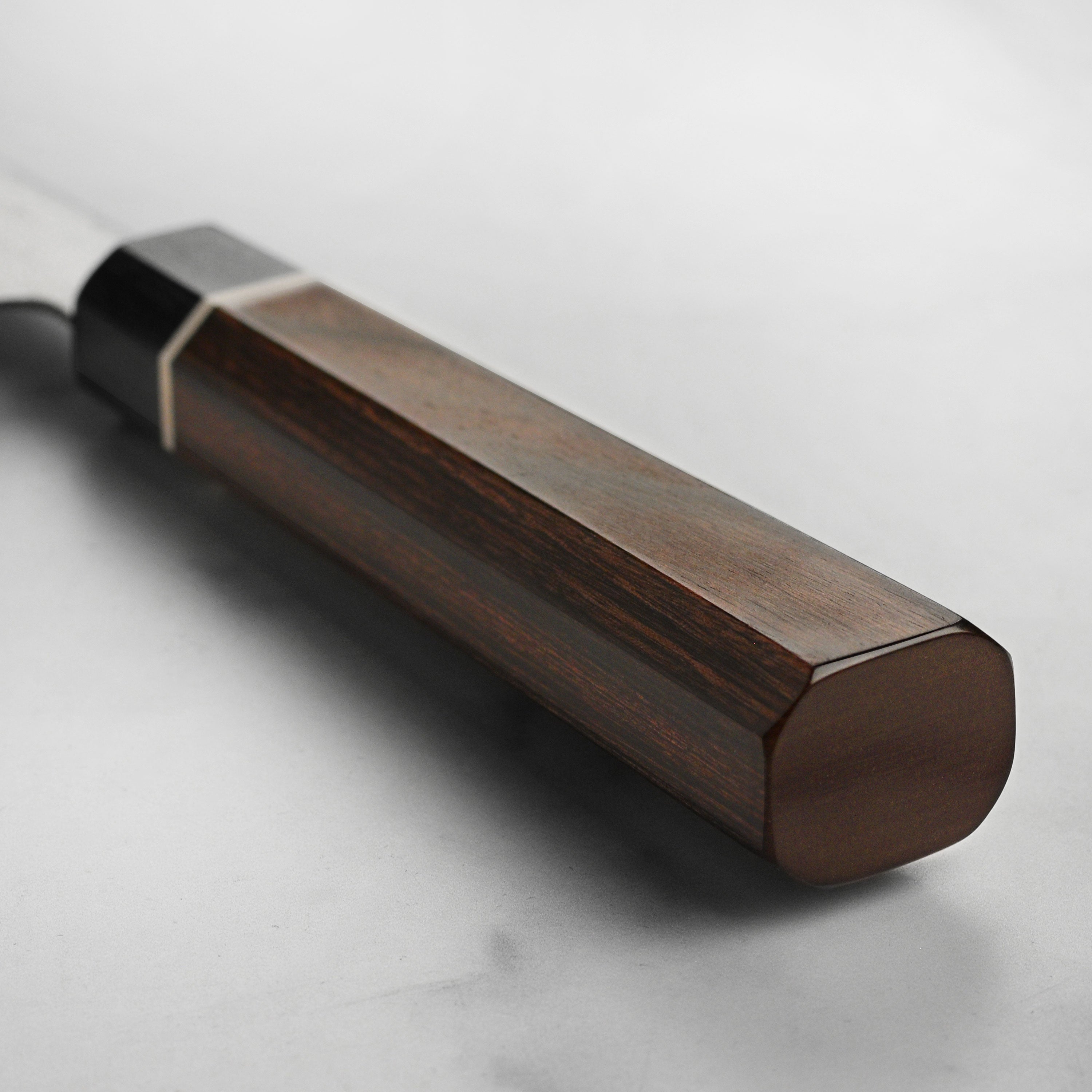 Close-up of the brown and black Pakkawood handle of the Suncraft Damascus knife.