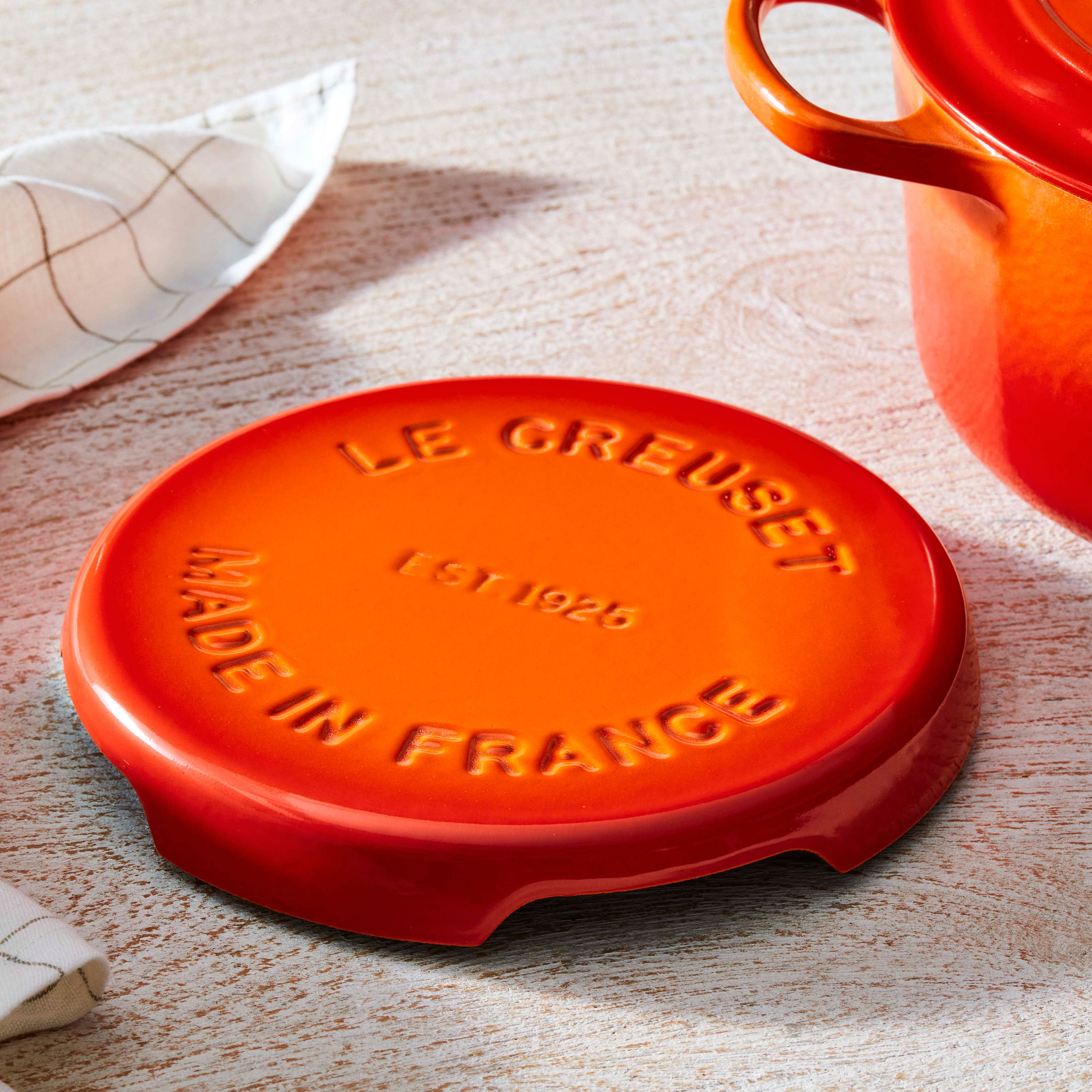 Le Creuset cast iron trivet protecting a dining table with hot dishes