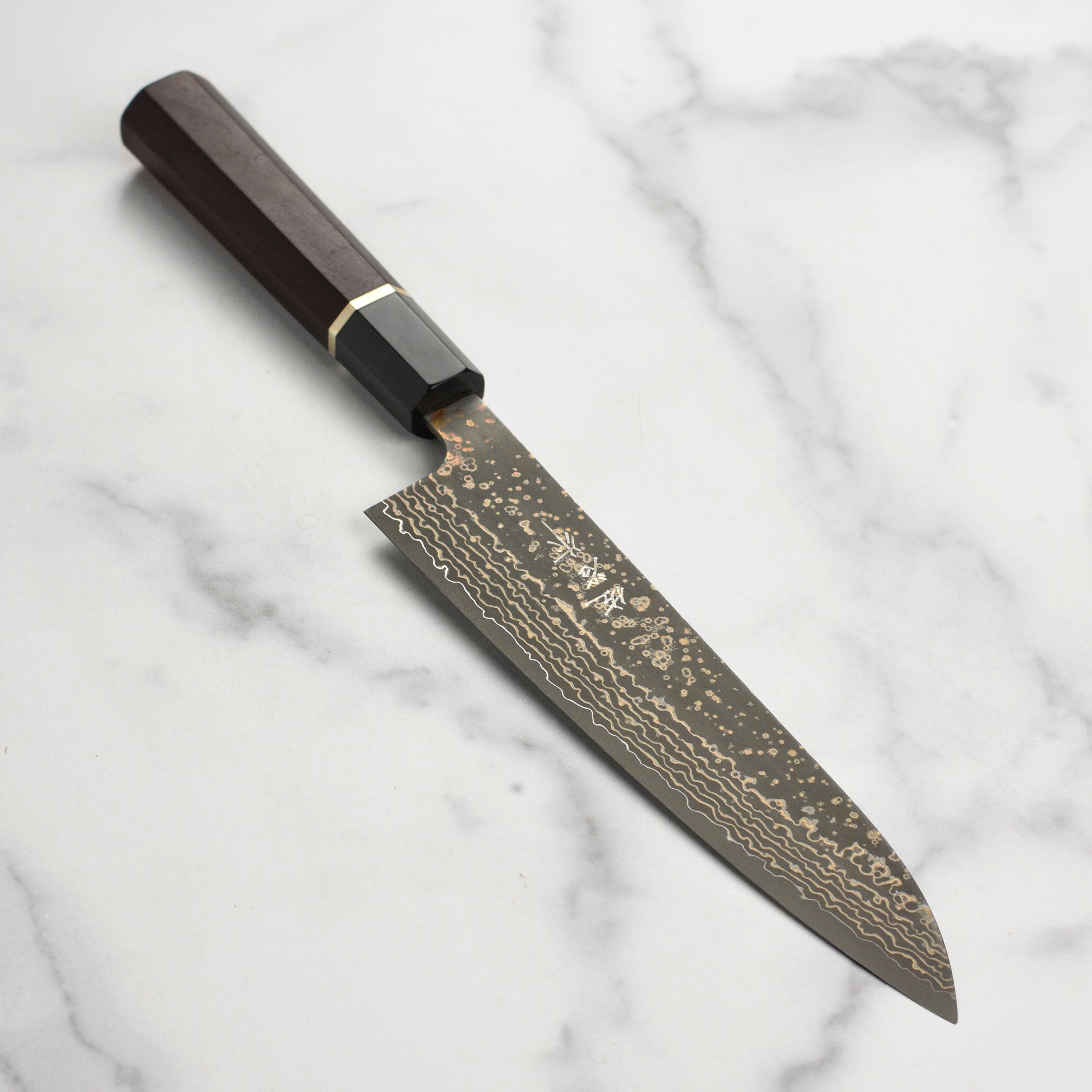 Close-up of the Saji Black Gold Damascus knife, highlighting its detailed blade design and craftsmanship.
