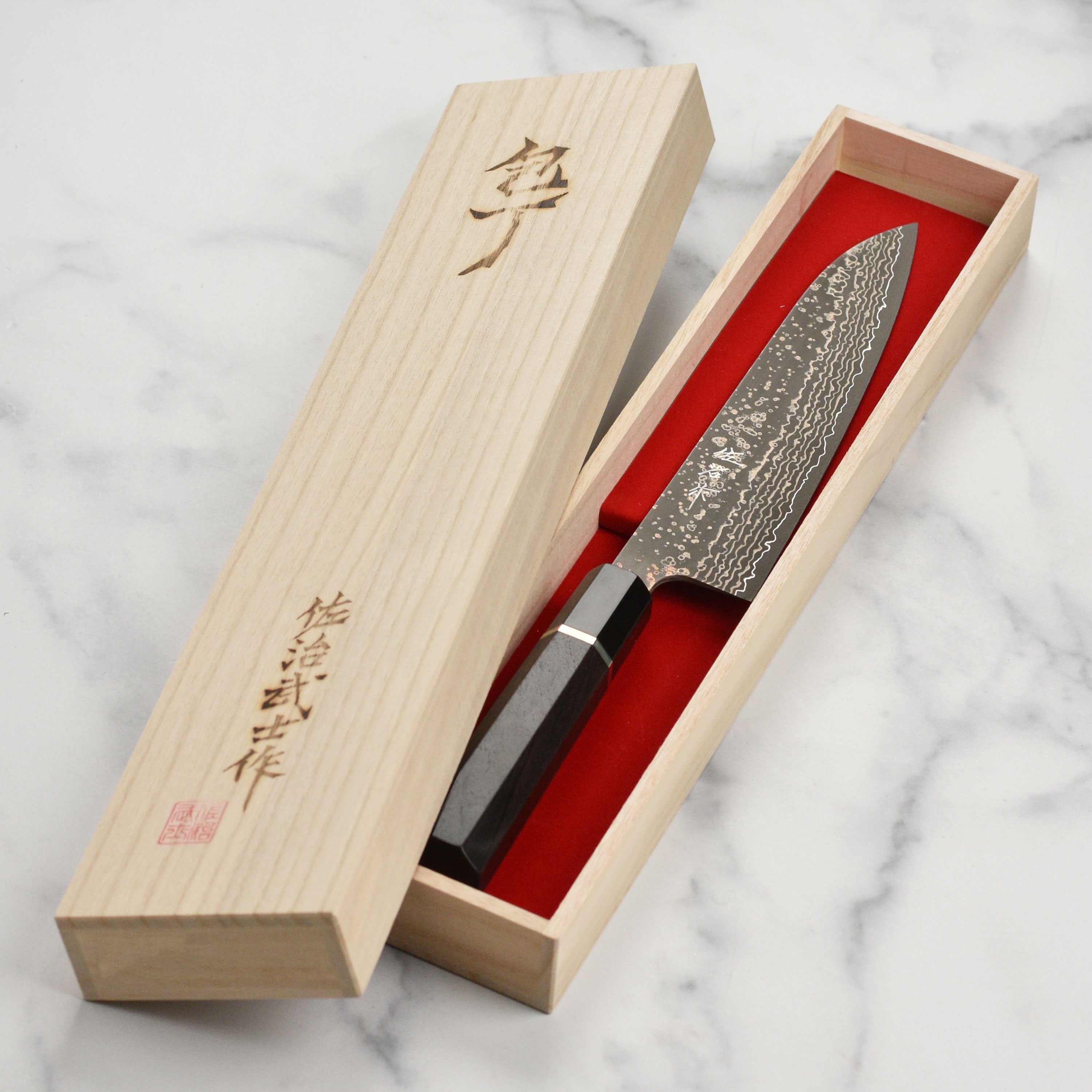 Saji Black Gold Damascus chef knife resting on a wooden cutting board, ready for culinary use.
