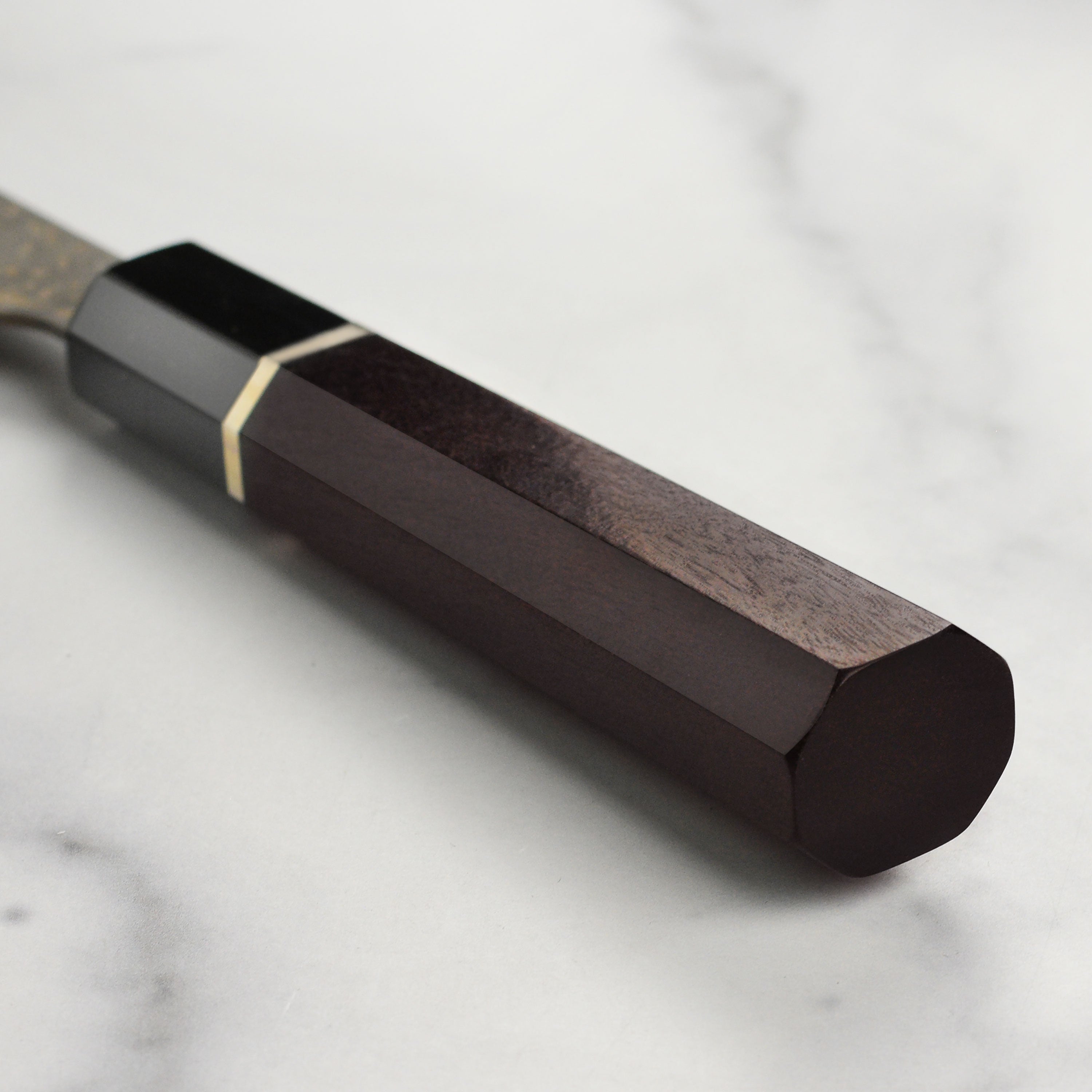 Saji Black Gold Damascus knife in a kitchen setting, demonstrating its use in food preparation.