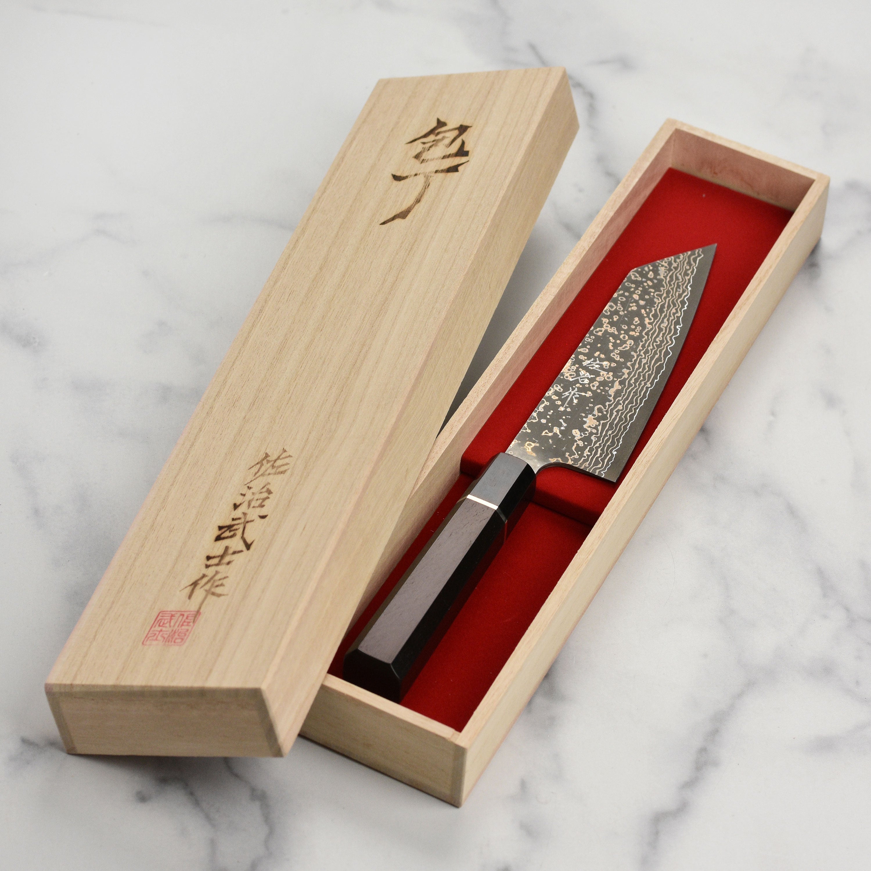 Saji Black Gold Damascus knife in a kitchen setting, demonstrating its use in food preparation.