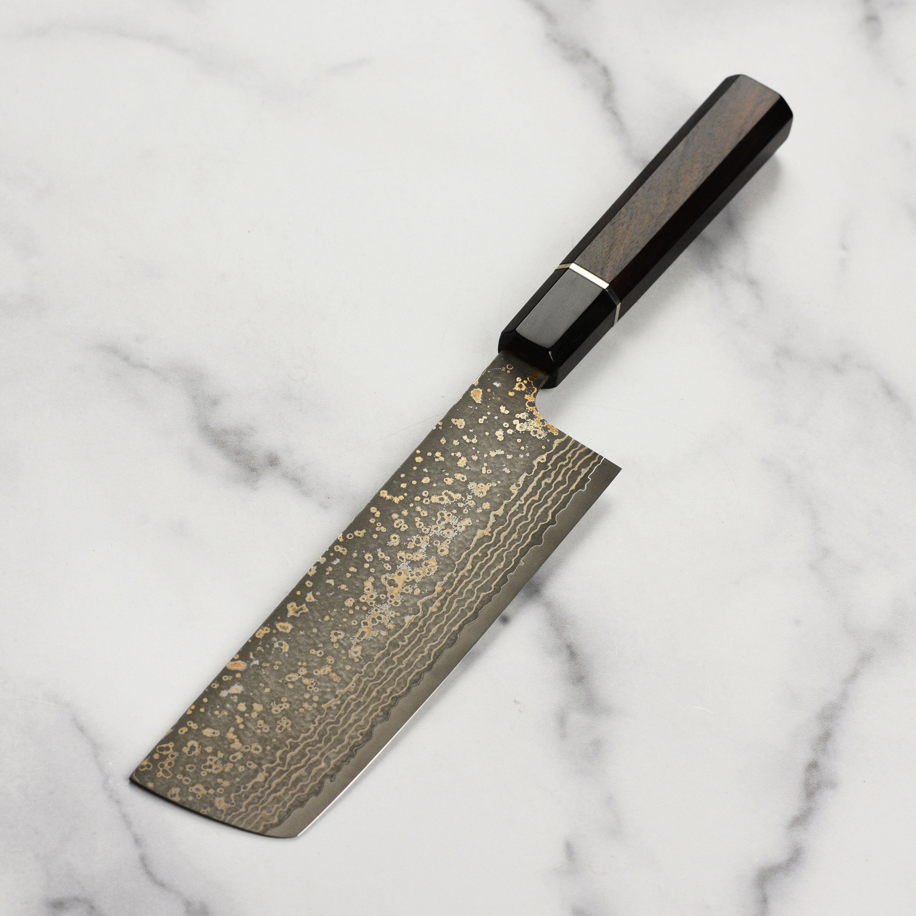 Saji Black Gold Damascus Nakiri in a kitchen setting with vegetable slicing
