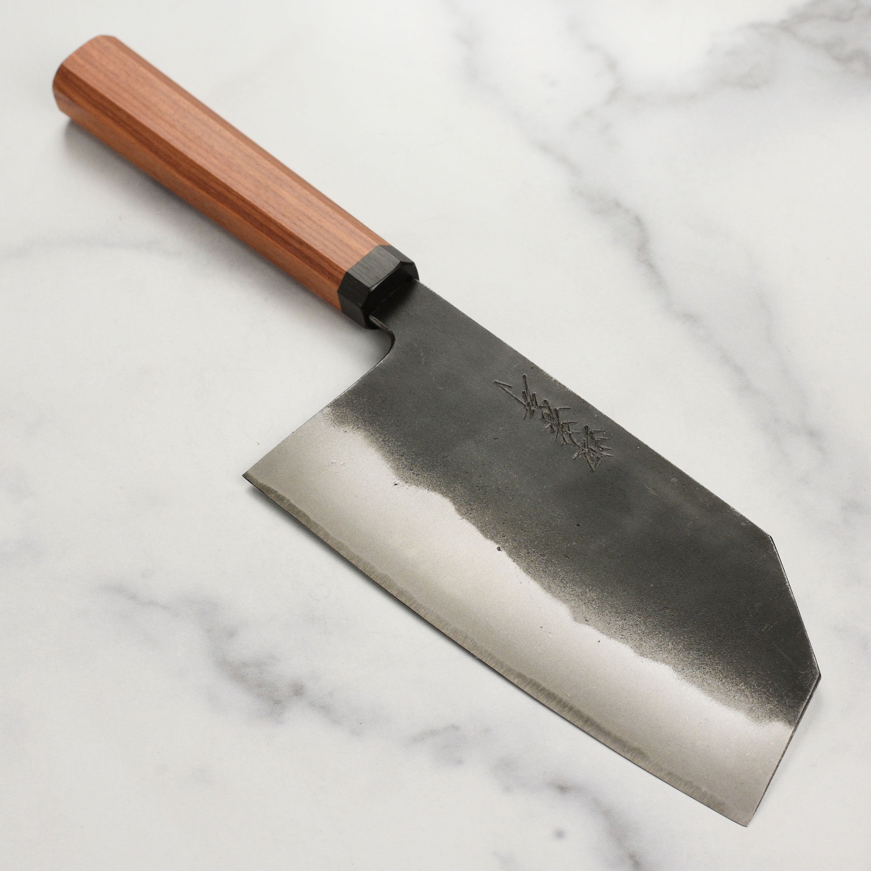 Close-up of Takayuki Tokujo Shirogami Bunka knife blade highlighting its sharp edge and kurouchi finish.