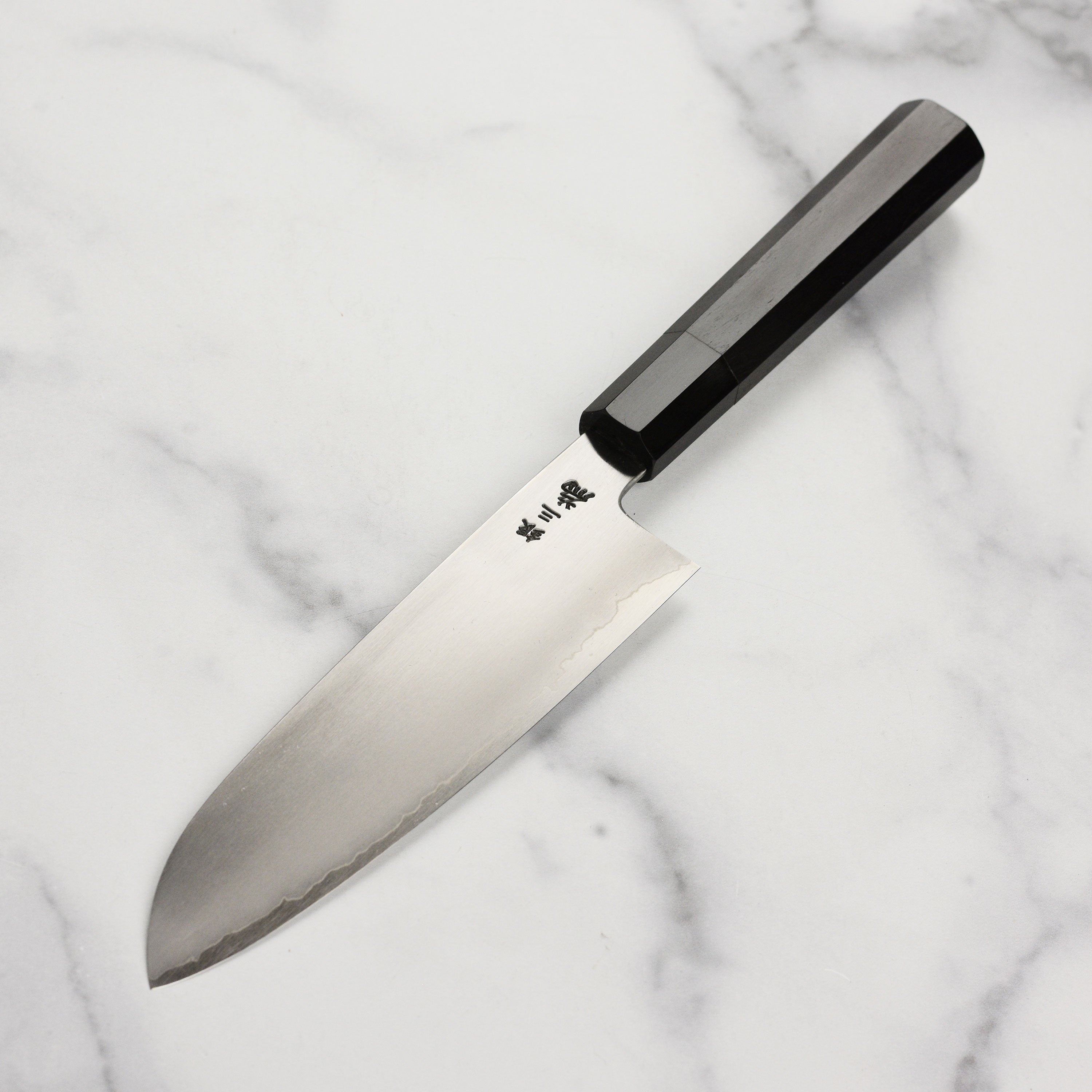 Profile view of the Santoku knifes ebony wood handle and buffalo horn ferrule.