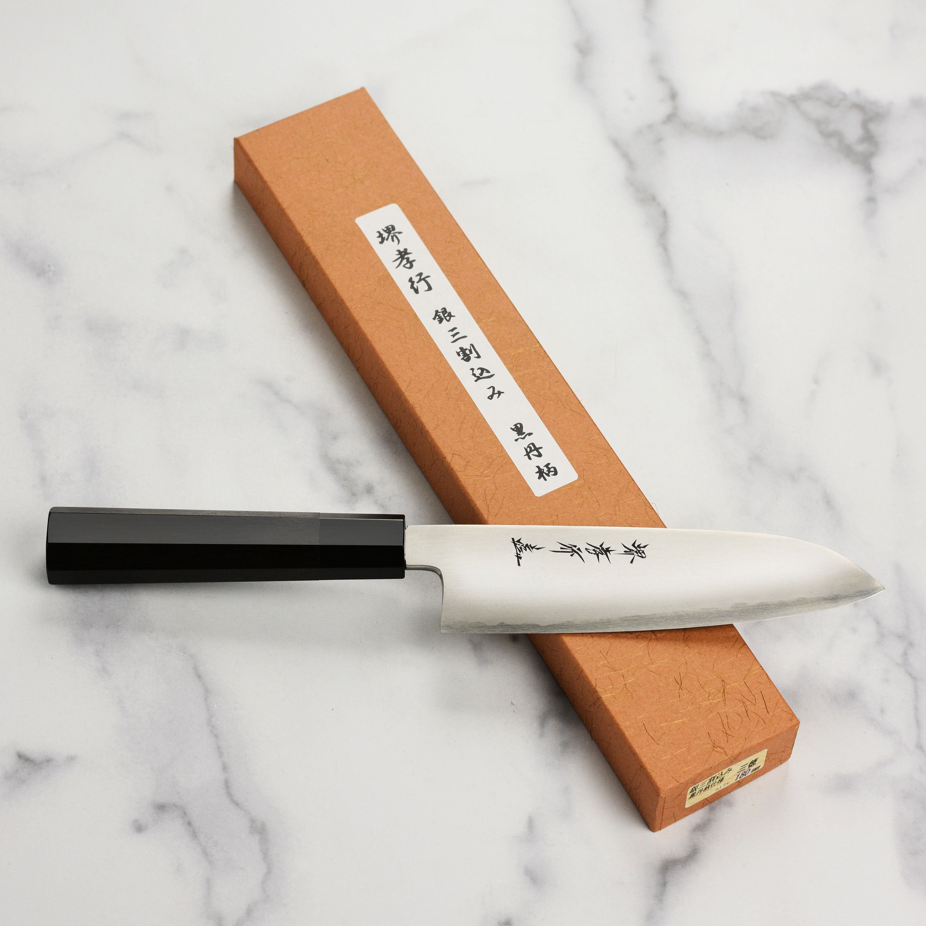 Profile view of the Santoku knifes ebony wood handle and buffalo horn ferrule.