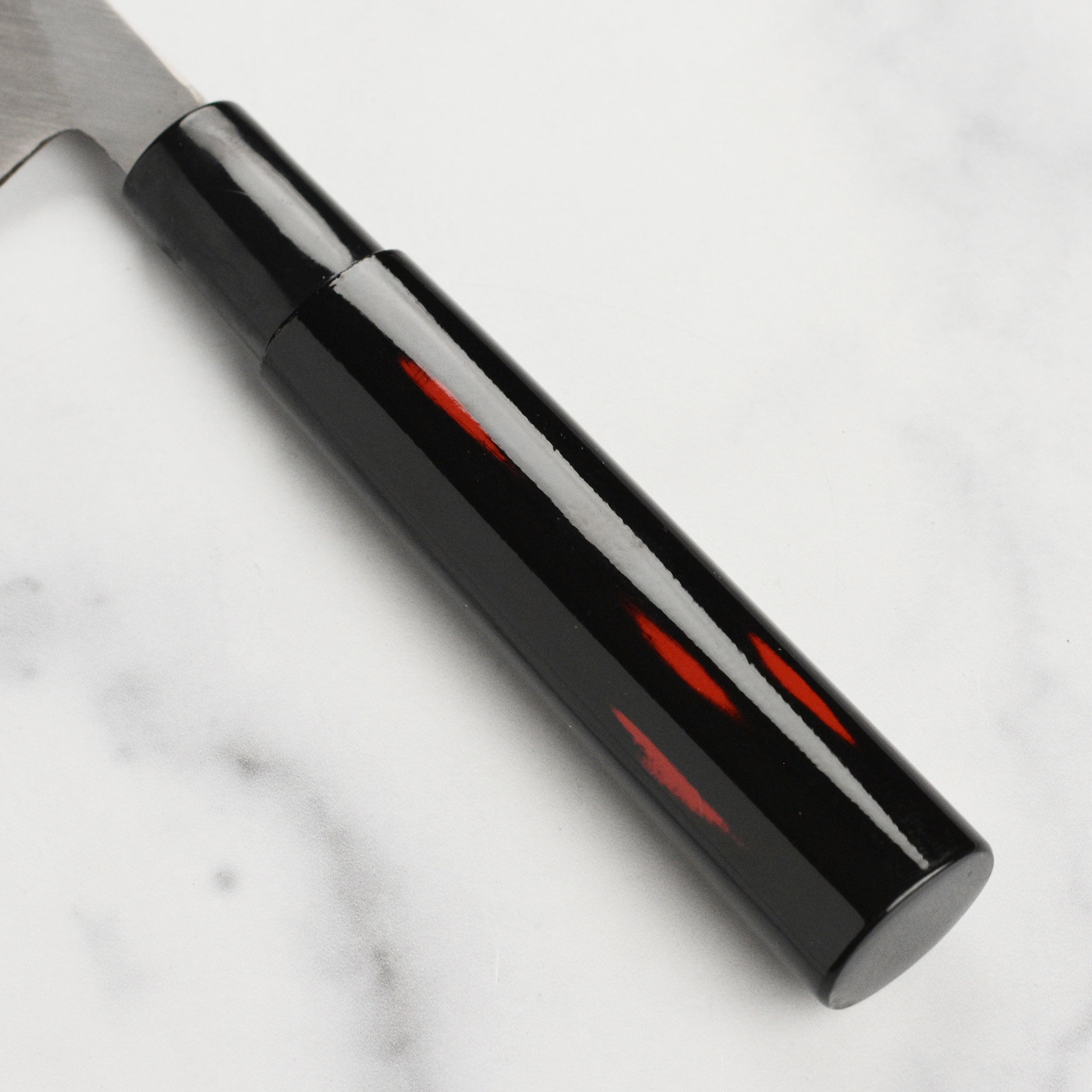 Close-up of the sharp carbon steel edge of the Shikisai Yanagiba knife, ideal for sushi and sashimi.