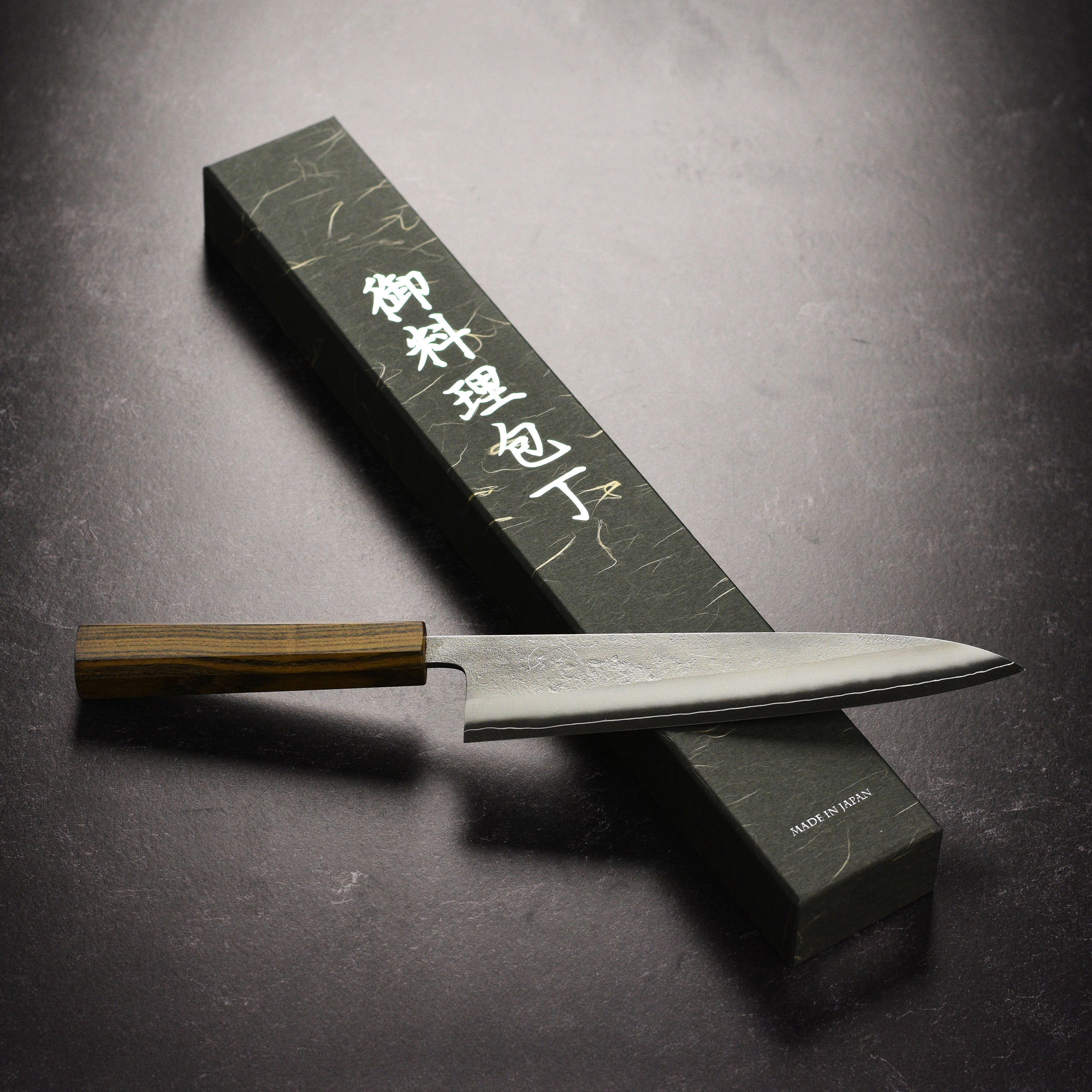 Yoshikane SKD gyuto knife in action, slicing vegetables on a kitchen countertop.