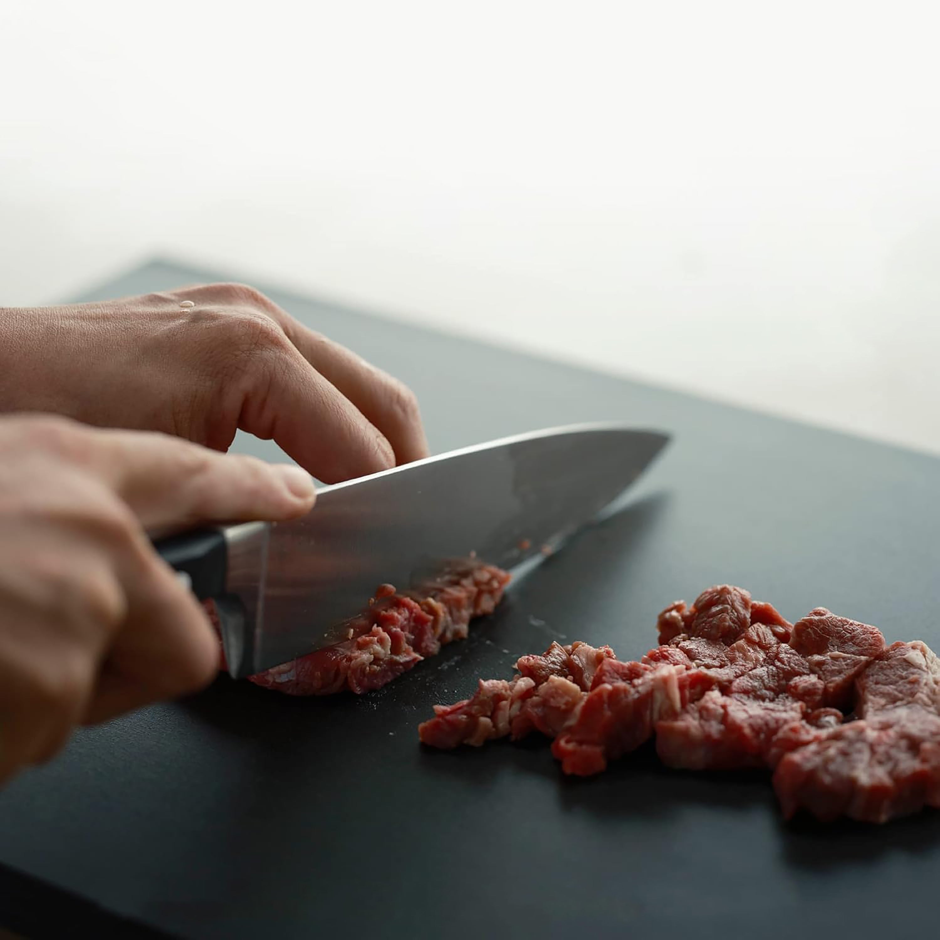Professional chef using the Asahi Elite Rubber Cutting Board for food preparation with vibrant ingredients.
