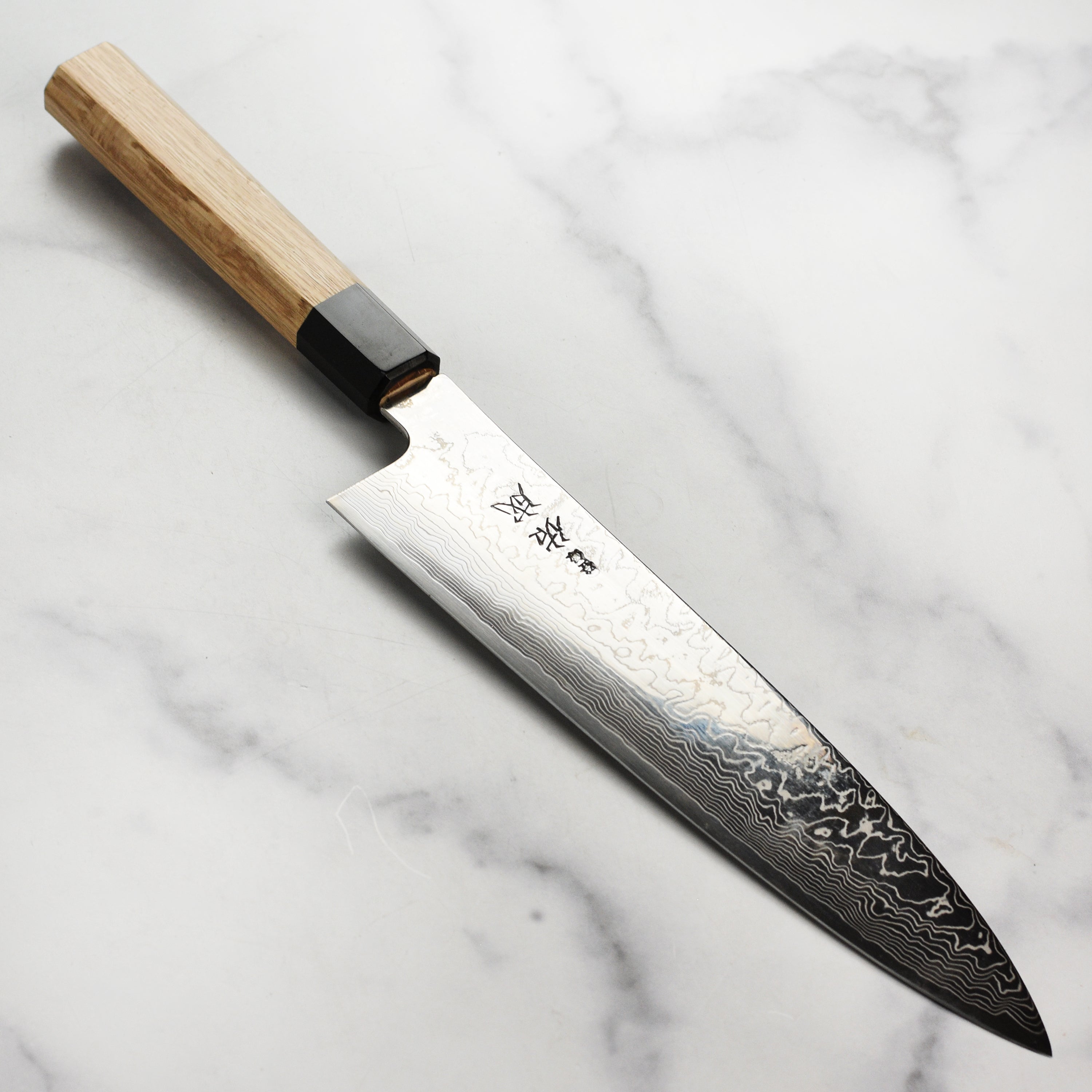Sukenari SG2 Gyuto knife on a wooden cutting board, highlighting its sharp blade and handle.
