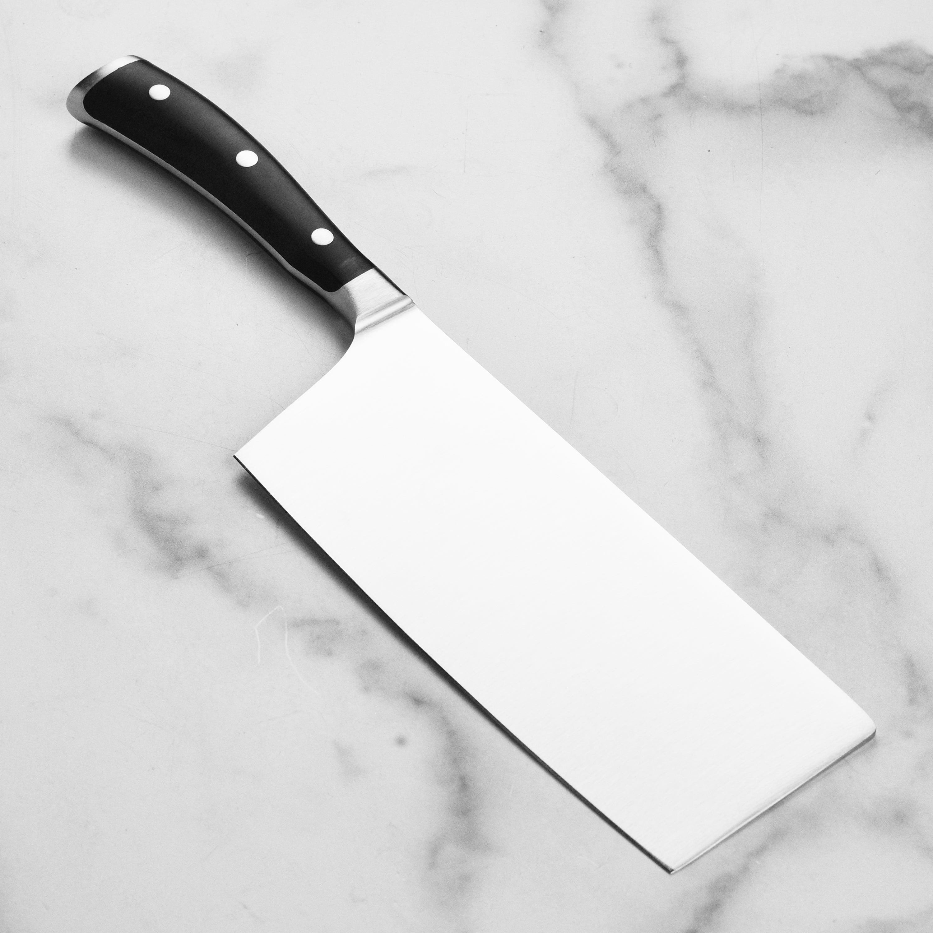 Close-up of Wusthof 7 inch Chinese chefs knife cutting vegetables with precision.