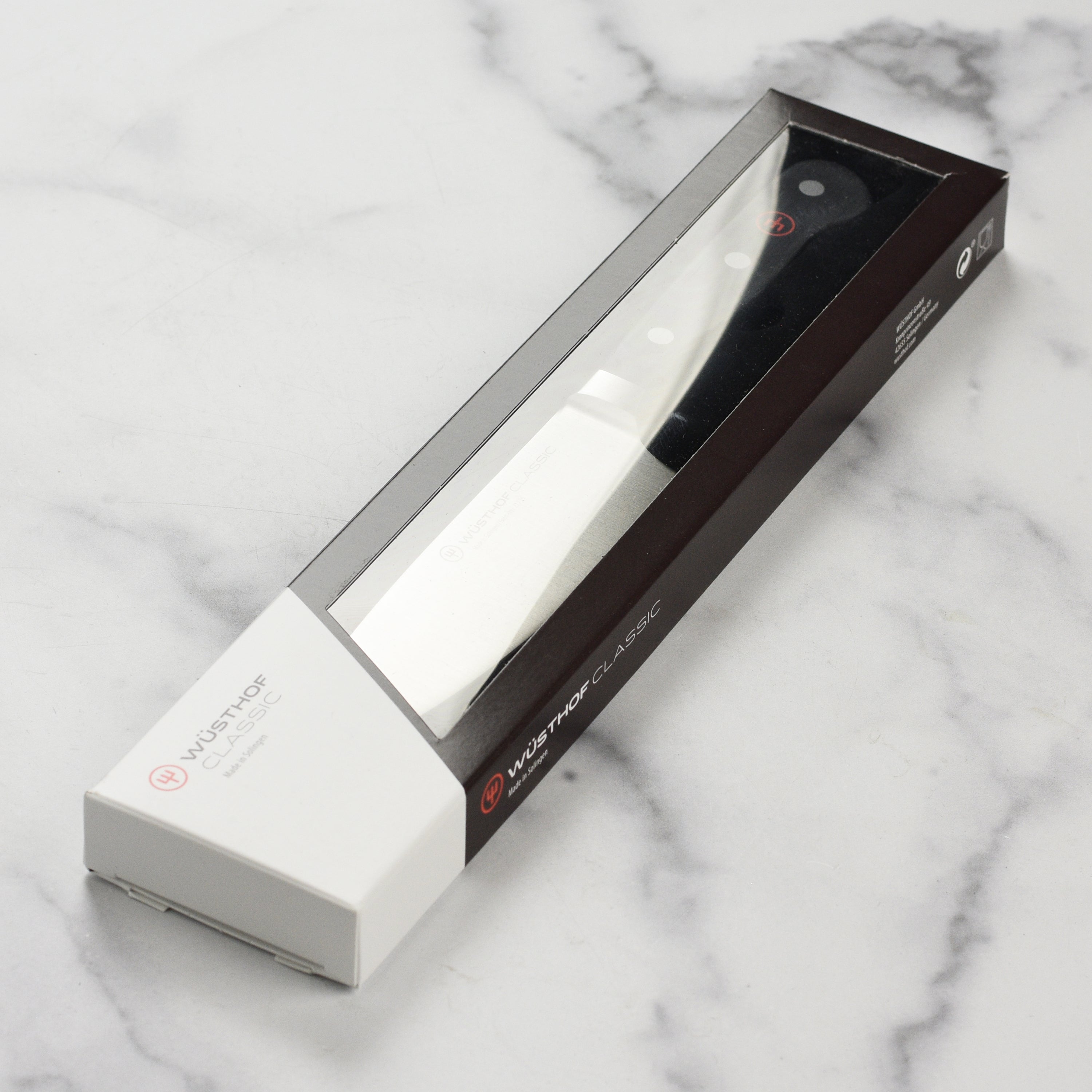 Wusthof Classic 6-Inch Chefs Knife displayed with a cutting board and fresh ingredients.