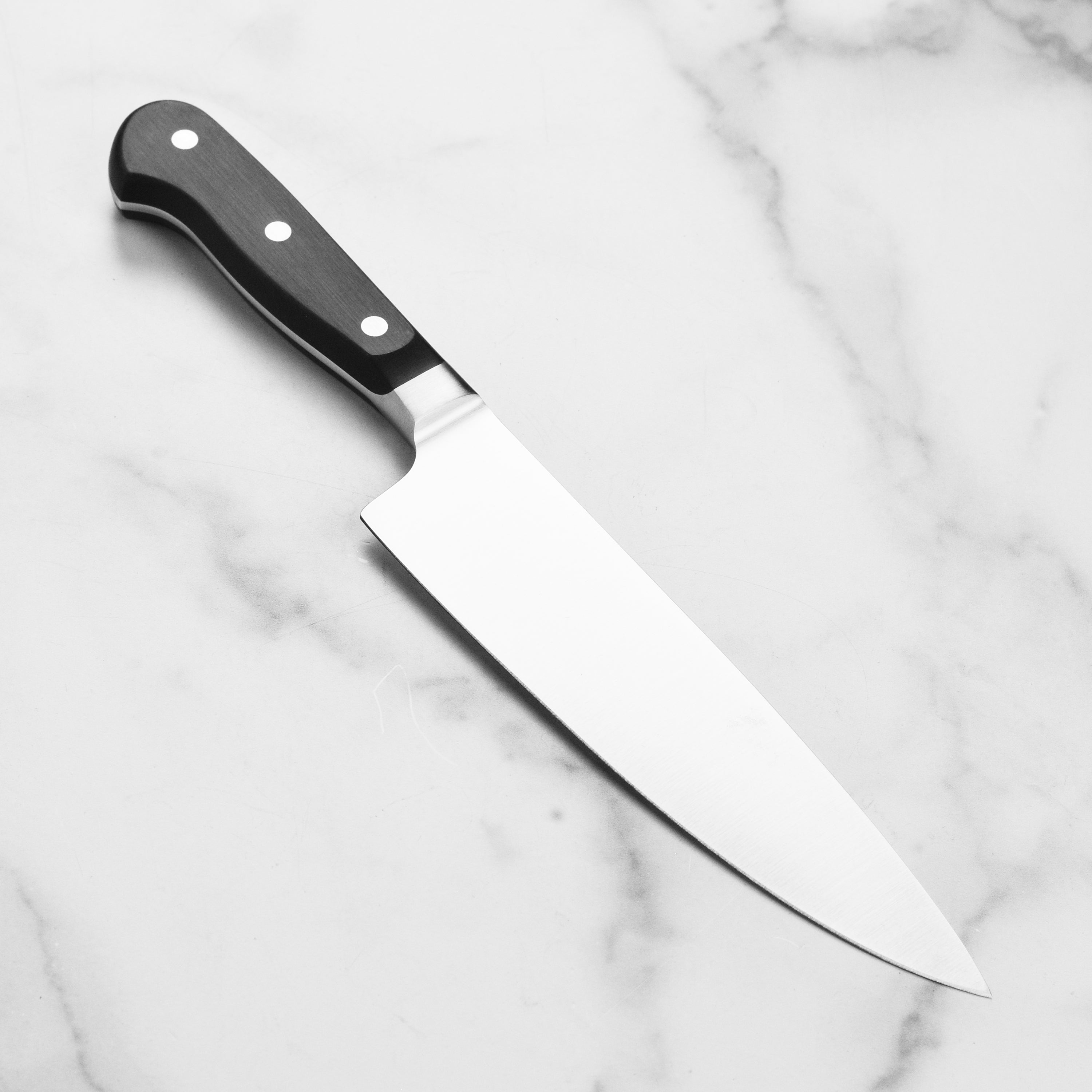 Professional chef knife in hand highlighting the full tang and durable handle design