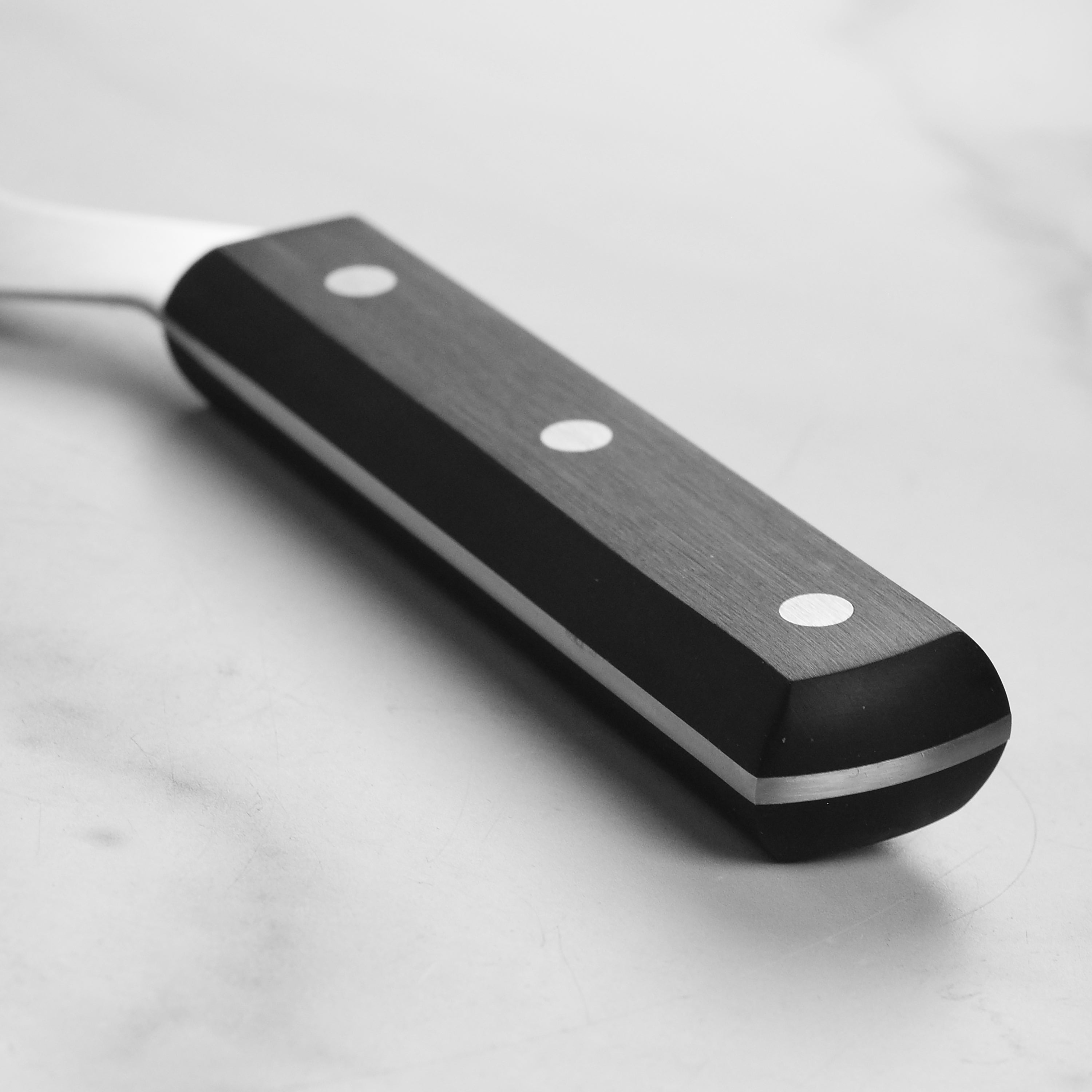 Close-up of the cheese cutter slicing through a soft cheese wheel.