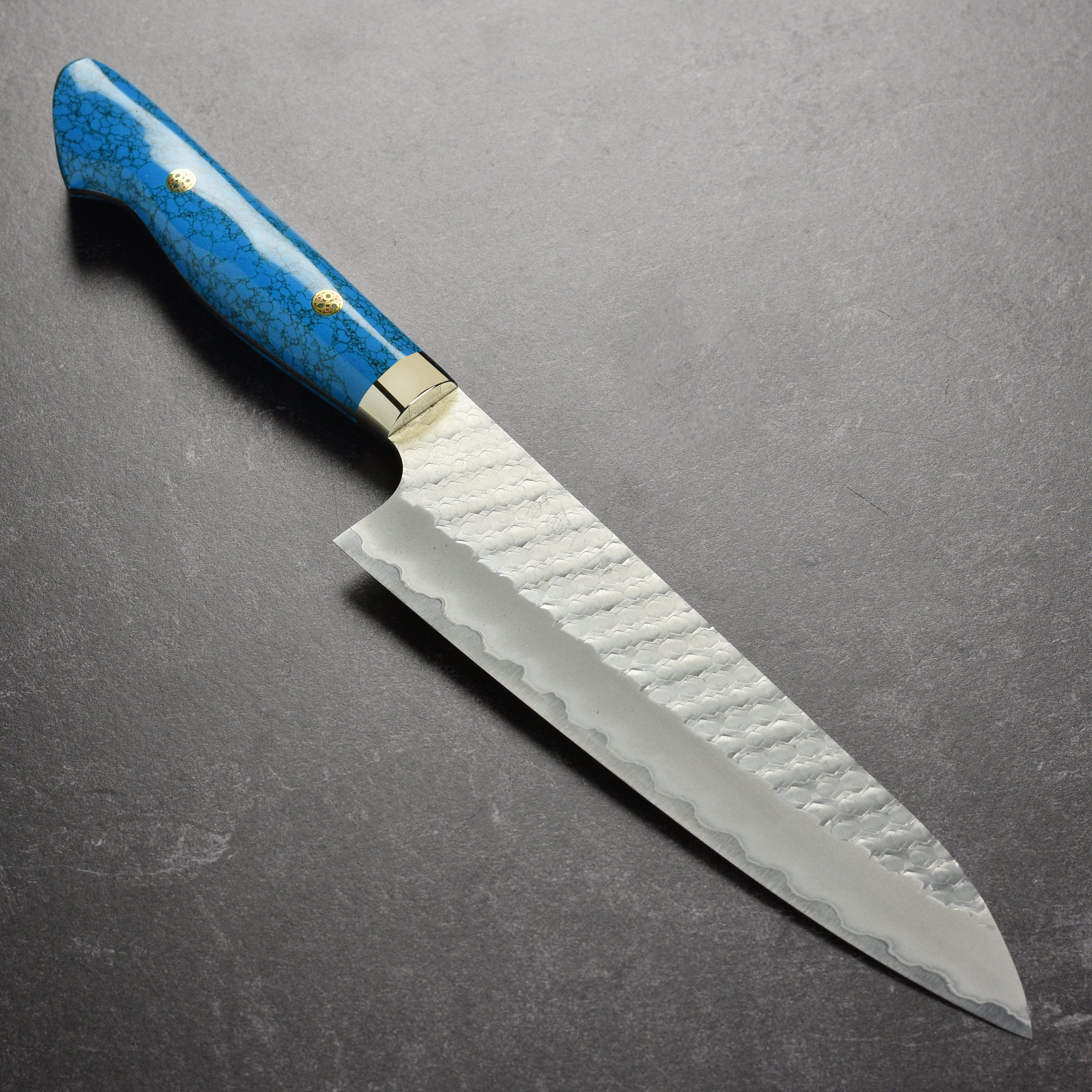 Side view of Nigara SG2 gyuto knife showing hammered tsuchime finish and blue turquoise handle
