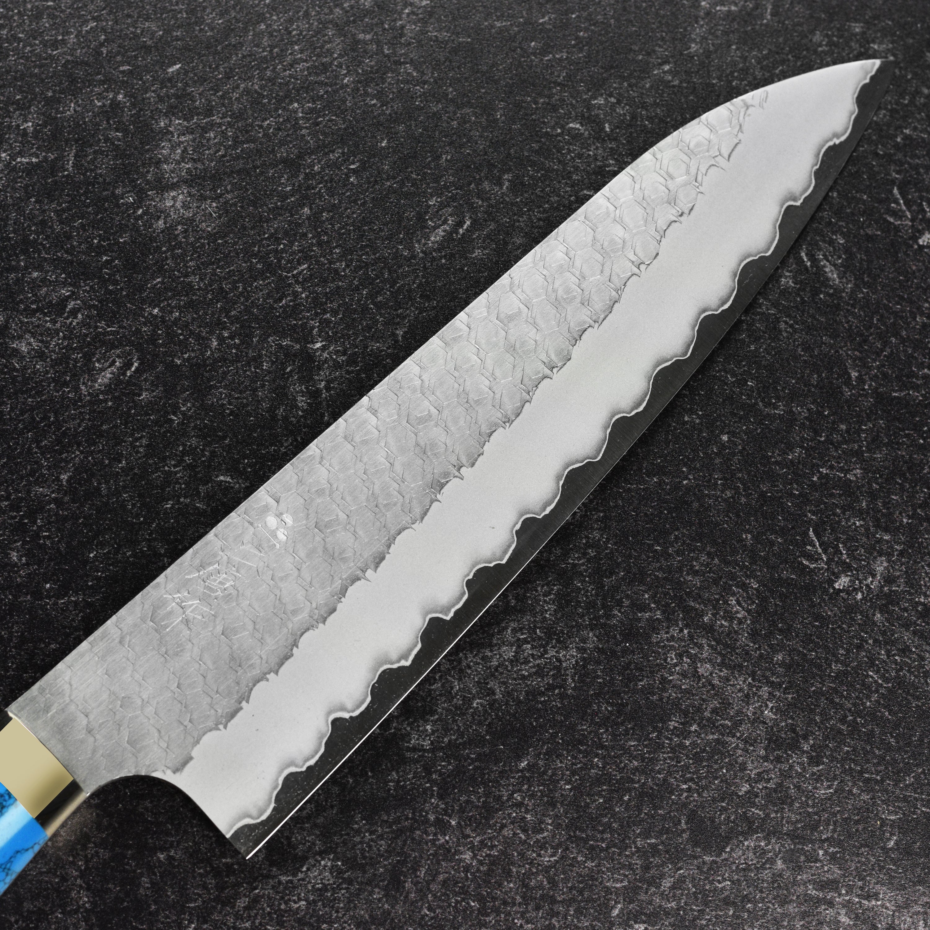 Side view of Nigara SG2 gyuto knife showing hammered tsuchime finish and blue turquoise handle