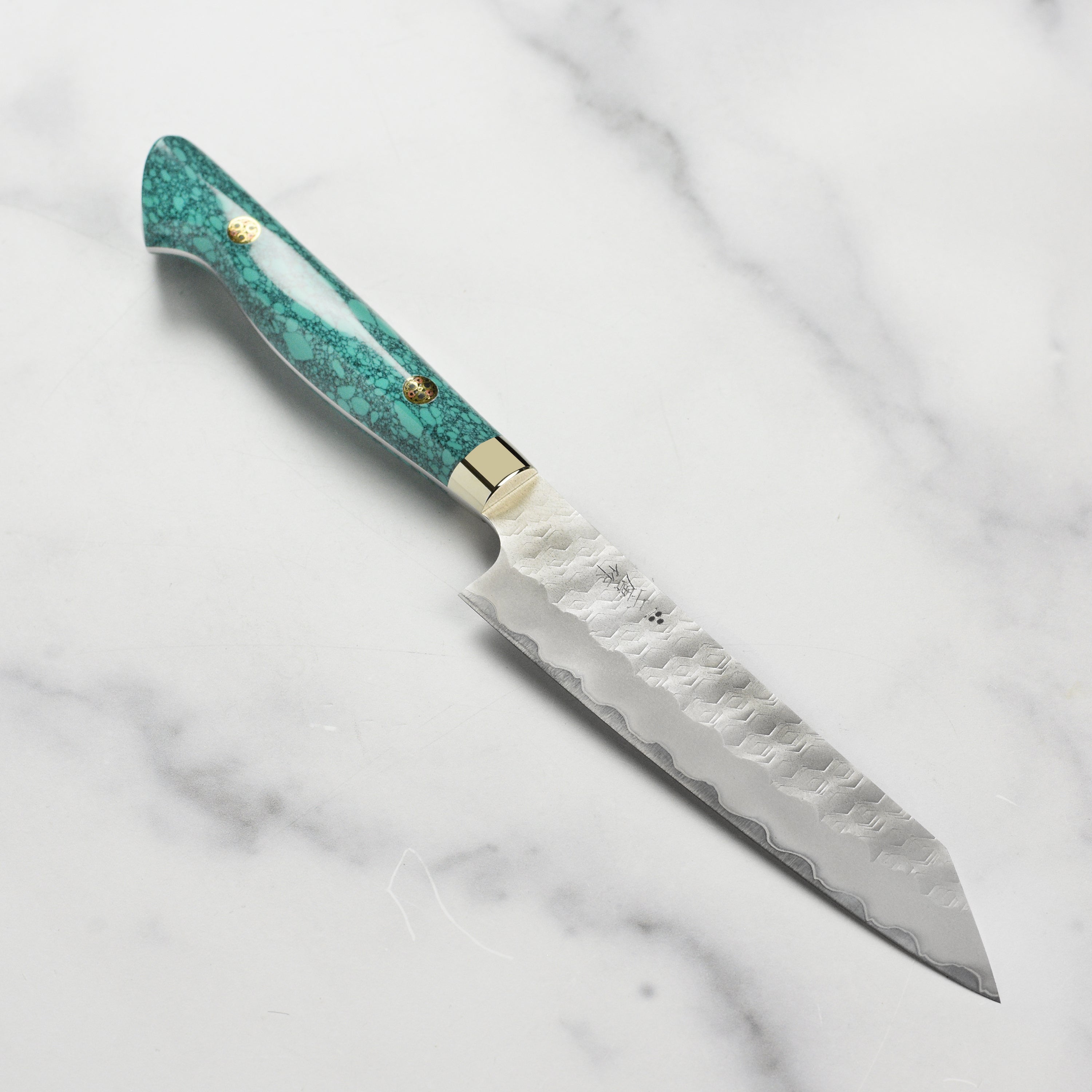 Close-up of the Nigara SG2 Kiritsuke petty knife showcasing the sharp blade and turquoise handle.