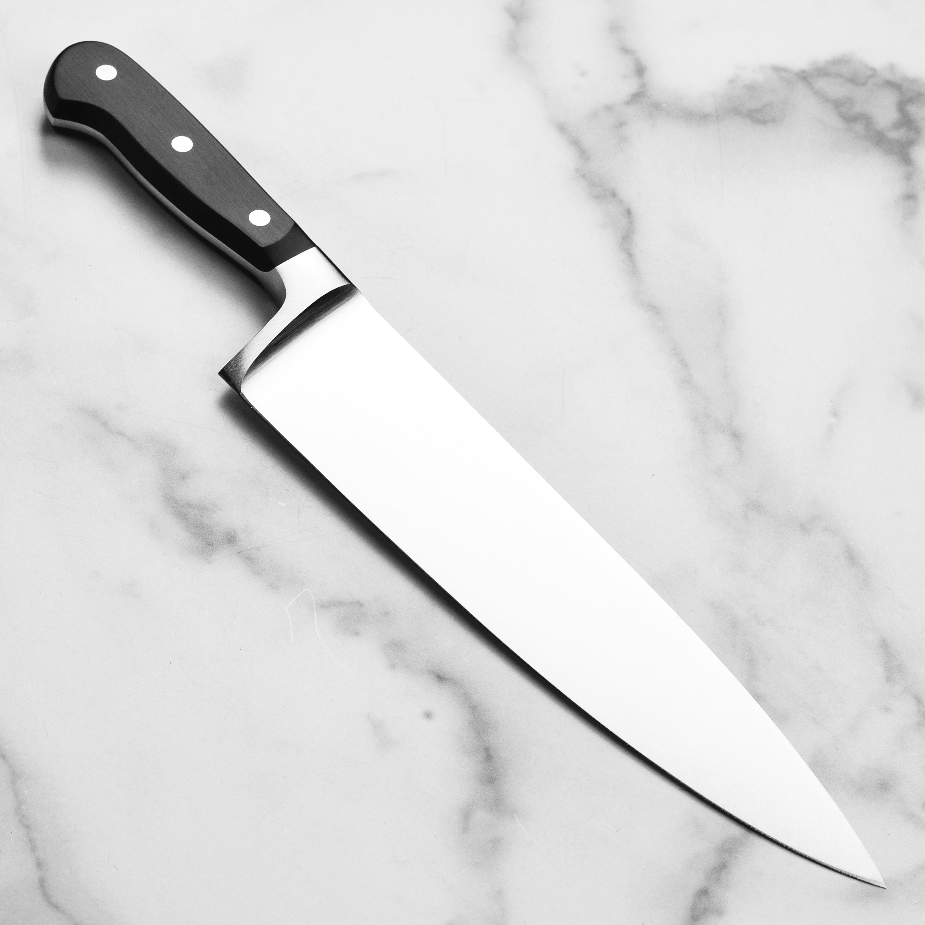 Top-down shot of the extra wide chefs knife slicing through root vegetables