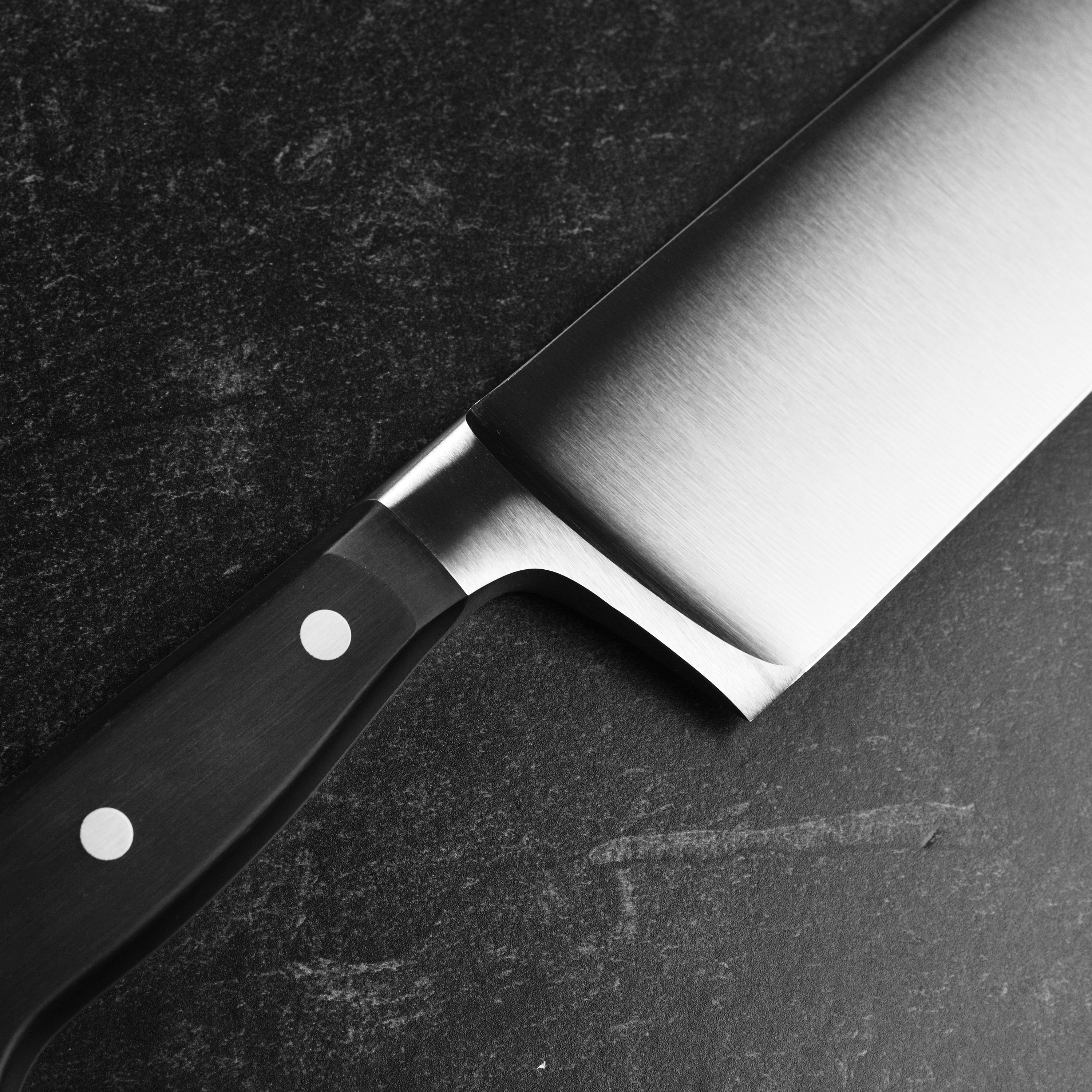 Top-down shot of the extra wide chefs knife slicing through root vegetables