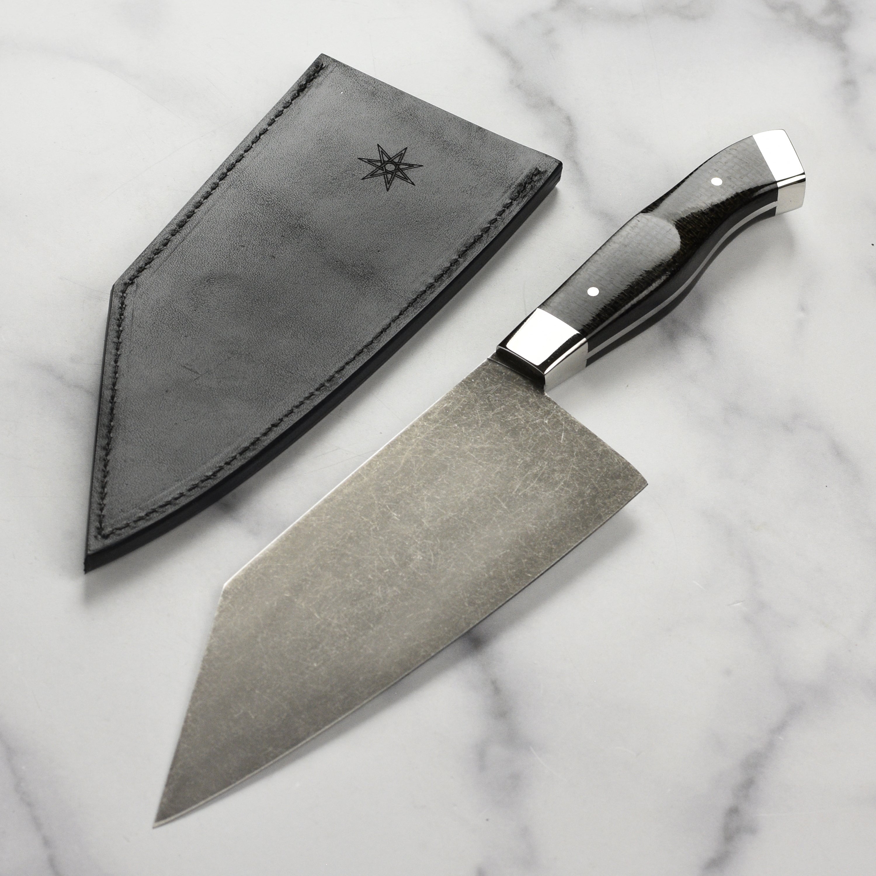 Close-up of the Reno Artisan handmade chef knife showing the carbon steel blade and micarta handle.