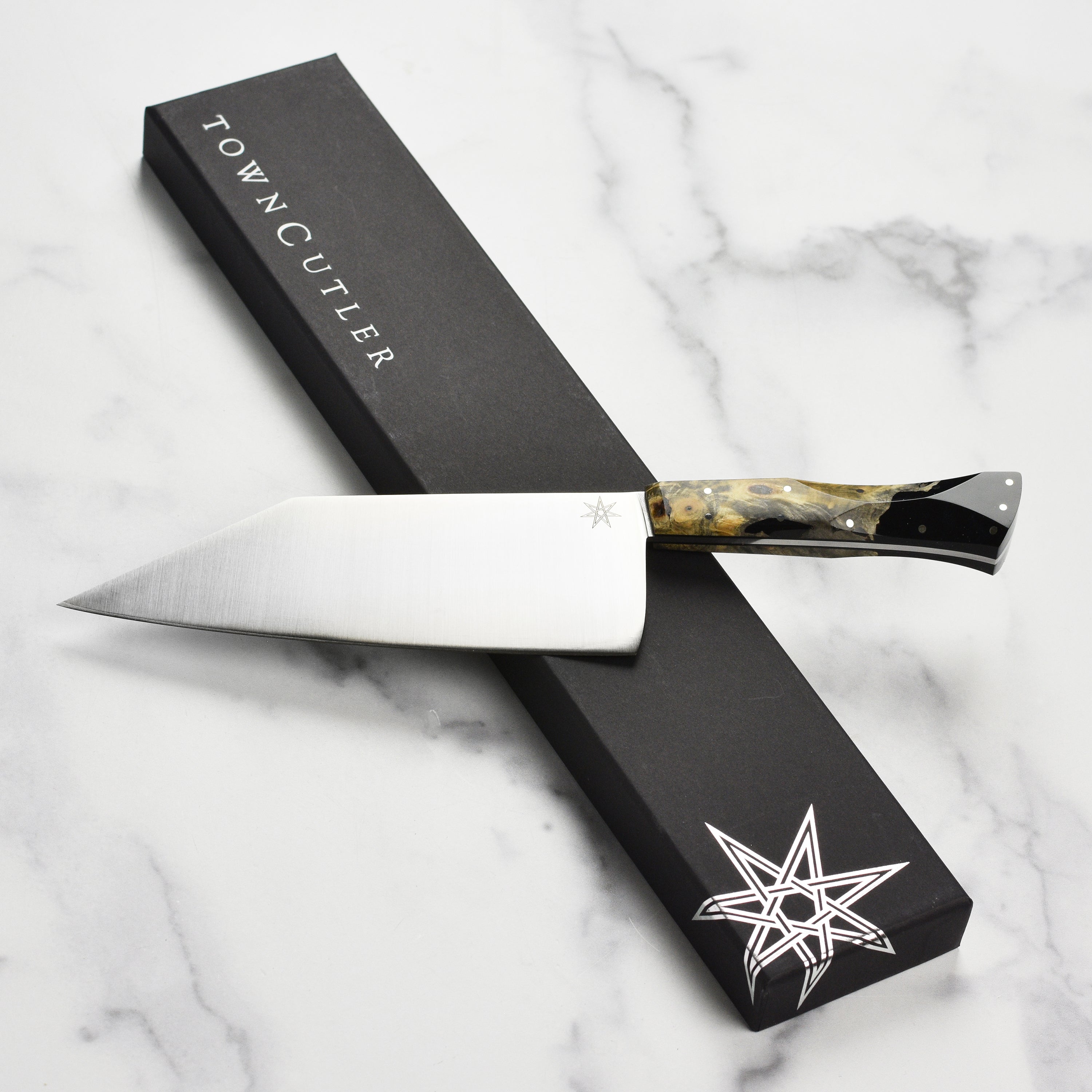 Desert Dawn chef knife with live-edge buckeye burl handle and stainless steel blade from an angle.