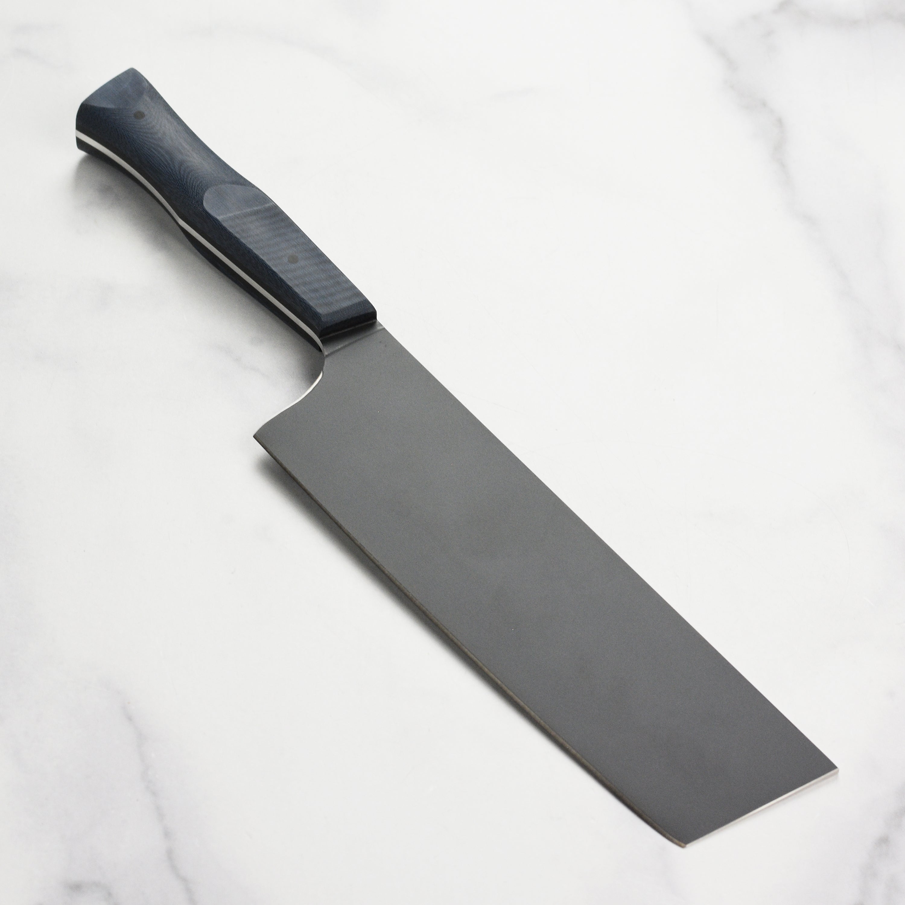 Town Cutler Nakiri knife in action, slicing vegetables on a cutting board.